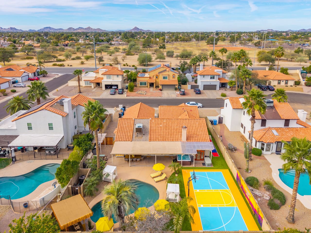 An aerial view says it all — pool, putting green, lounge seating, and desert views across this resort-style backyard.