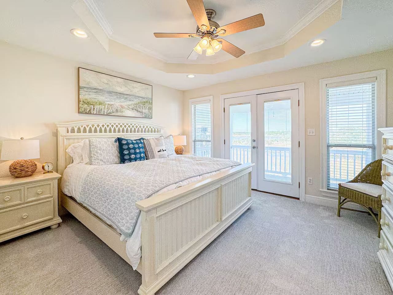 Relaxing primary bedroom with a plush king bed, soft coastal decor, and warm lighting. Includes bedside lamps, ceiling fan, and a peaceful, resort-style feel.