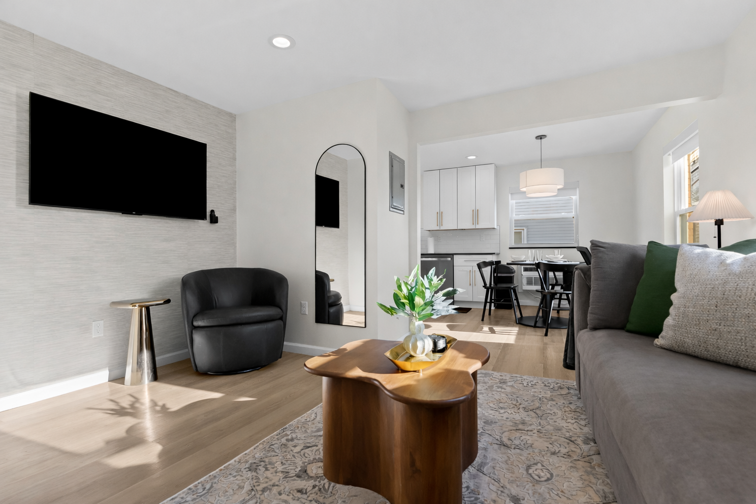 Sunlit living area with smart TV, cozy seating, and modern décor—flowing effortlessly into the dining and kitchen spaces for easy, comfortable living.