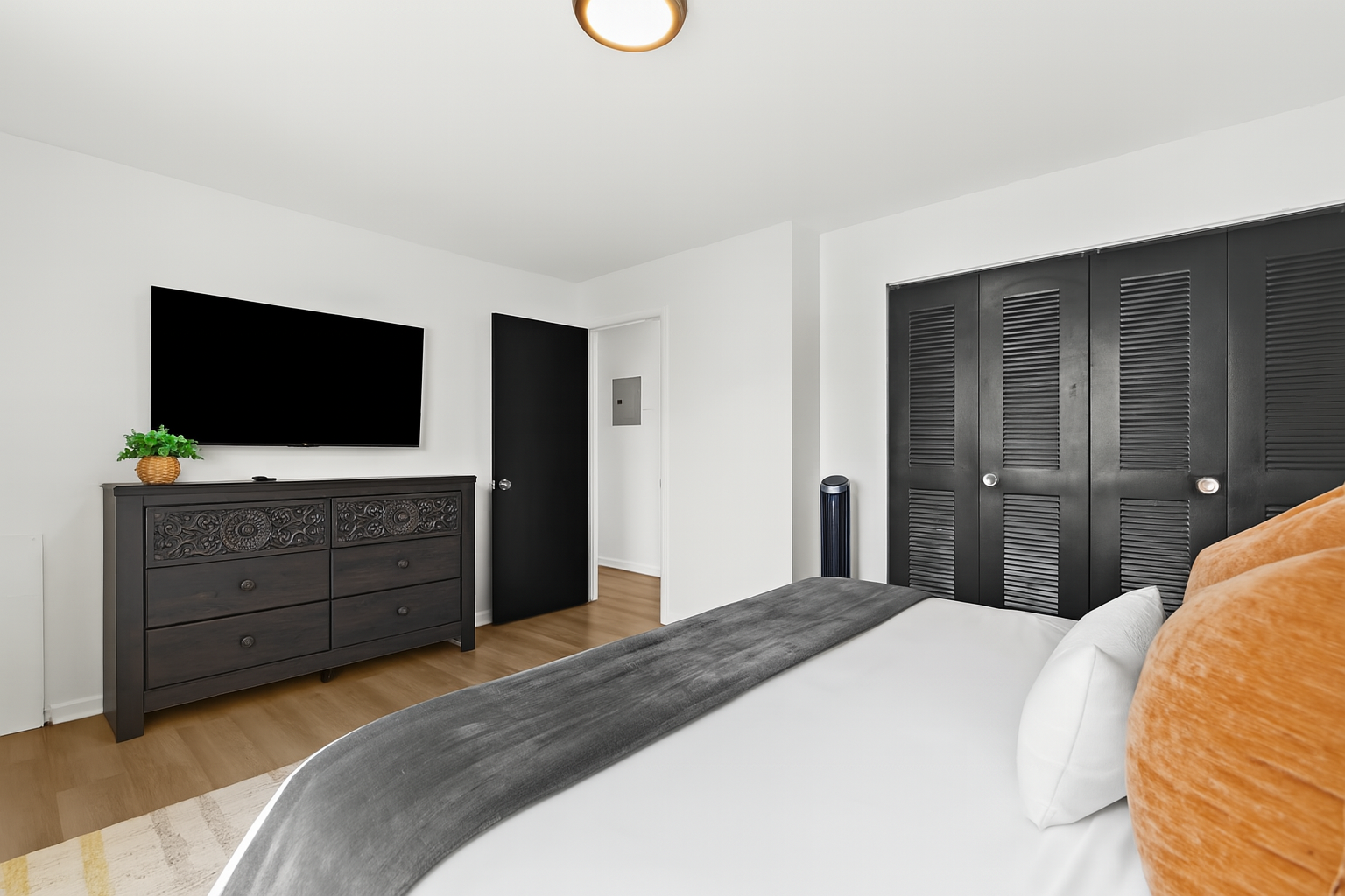 Unwind in a serene bedroom complete with a king bed, warm lighting, and modern wood paneling.