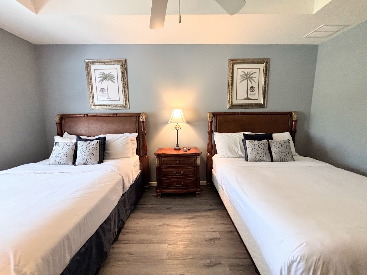 Cozy bedroom with two comfortable beds, matching nightstand, and simple neutral decor.