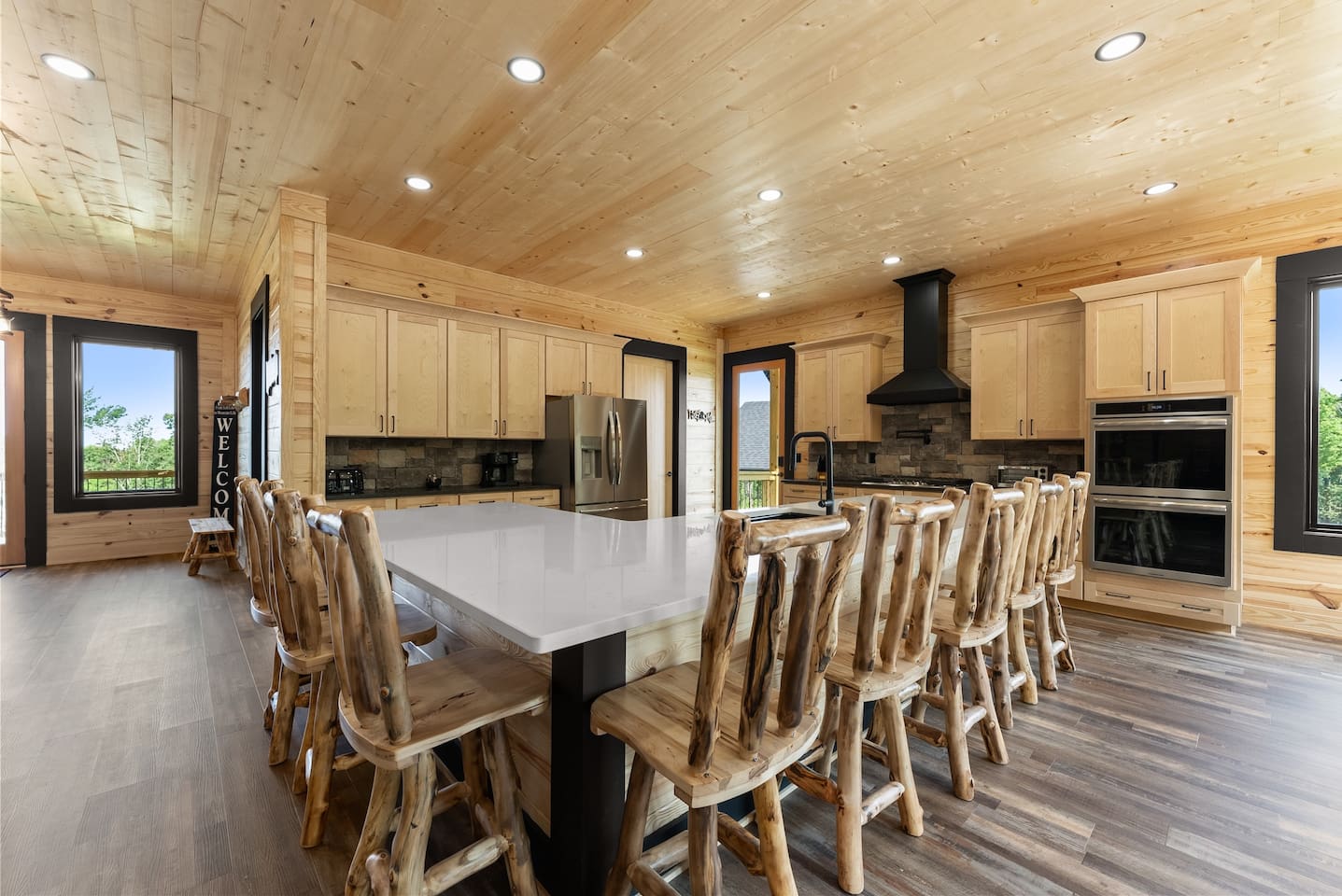 The dining space flows into an expansive kitchen island with custom log stools—perfect for large gatherings or buffet-style meals.