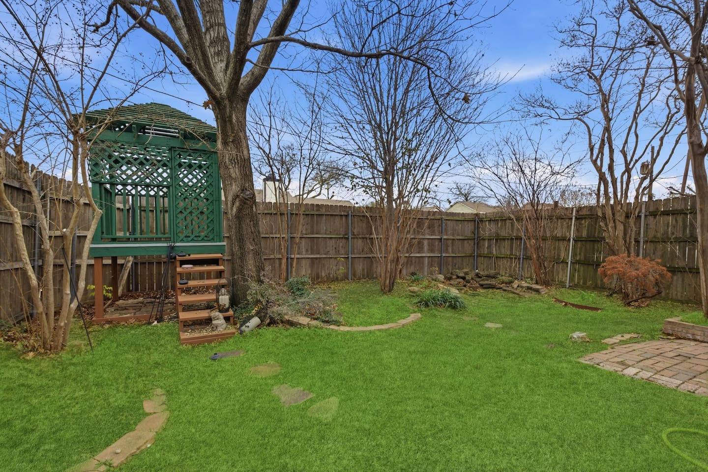 Fully fenced backyard with a raised gazebo, outdoor seating, high privacy fencing, and open space to relax or enjoy fresh air.