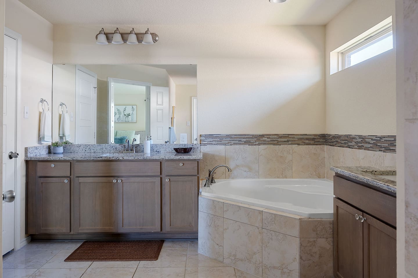 Explore this stylish bathroom featuring a large vanity, a luxurious soaking tub, and tasteful tile accents.