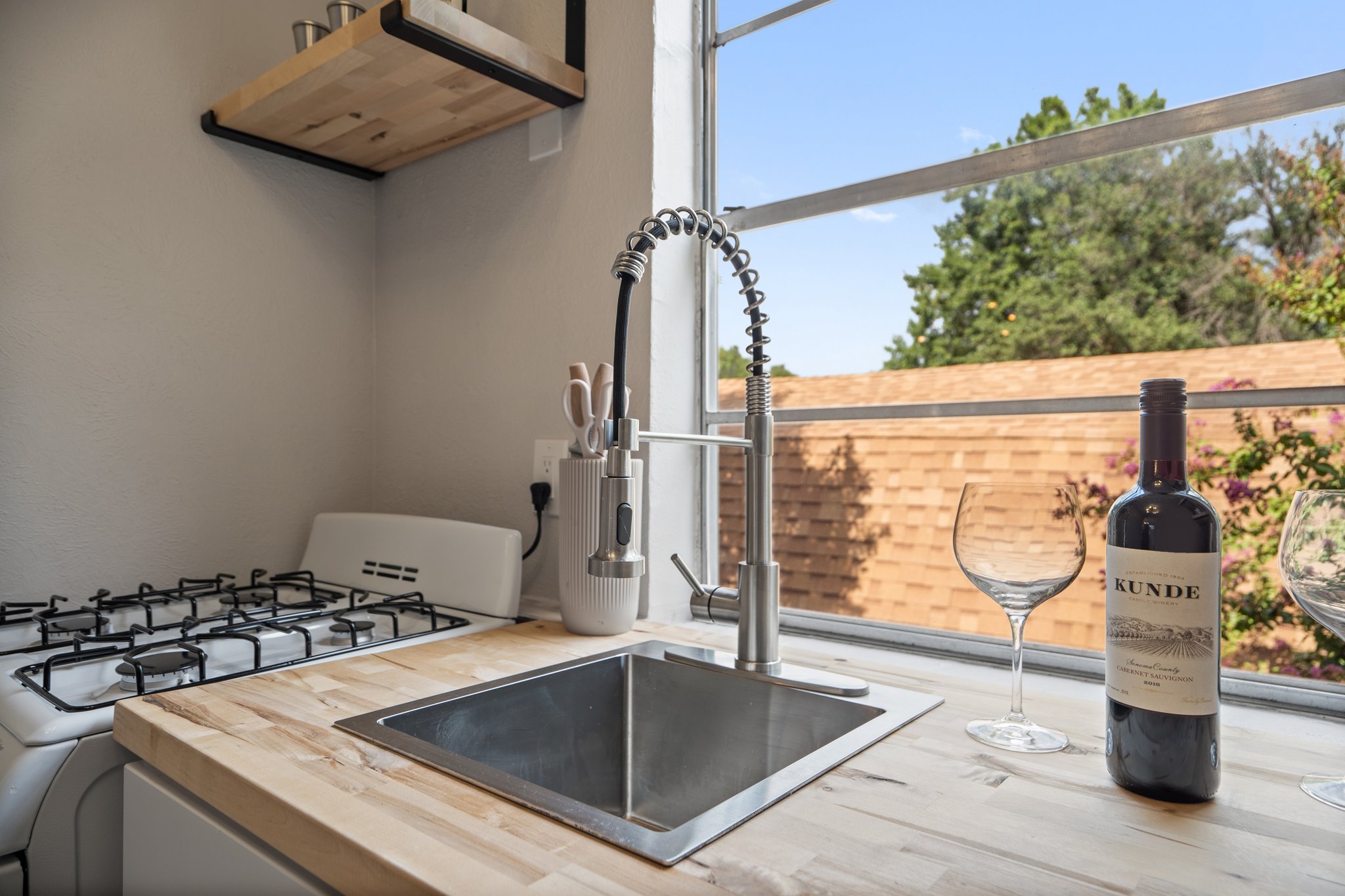 Detached Studio kitchen with undermount sink, gas range, and wine glasses. Fully stocked with cookware, dishes, silverware, cooking basics, and Keurig coffee maker. Completely self-contained unit.