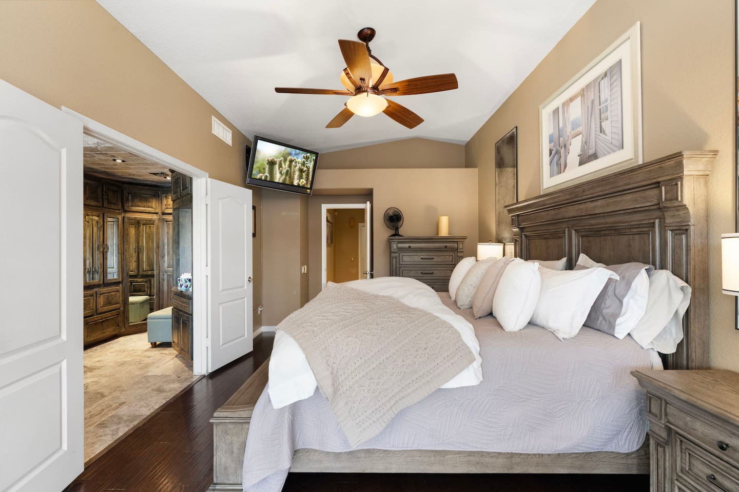 Retreat to the primary bedroom after a full day of fun — the king bed, ceiling fan, and wall-mounted TV make it easy to unwind without ever leaving the room. The ensuite bathroom is just steps away.