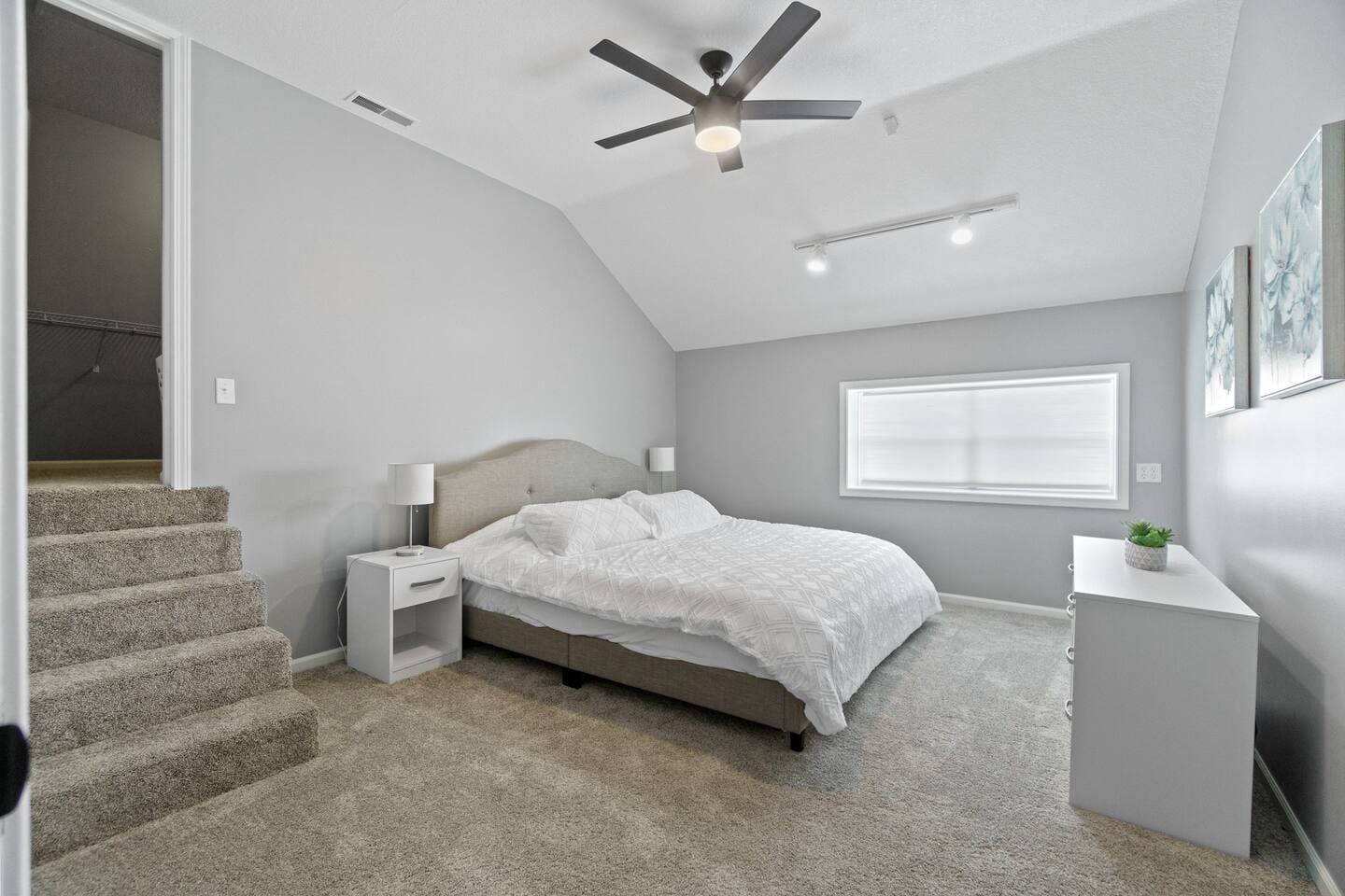 Spacious bedroom with a clean white interior and a large window, allowing natural light to fill the room and create a bright, airy atmosphere.