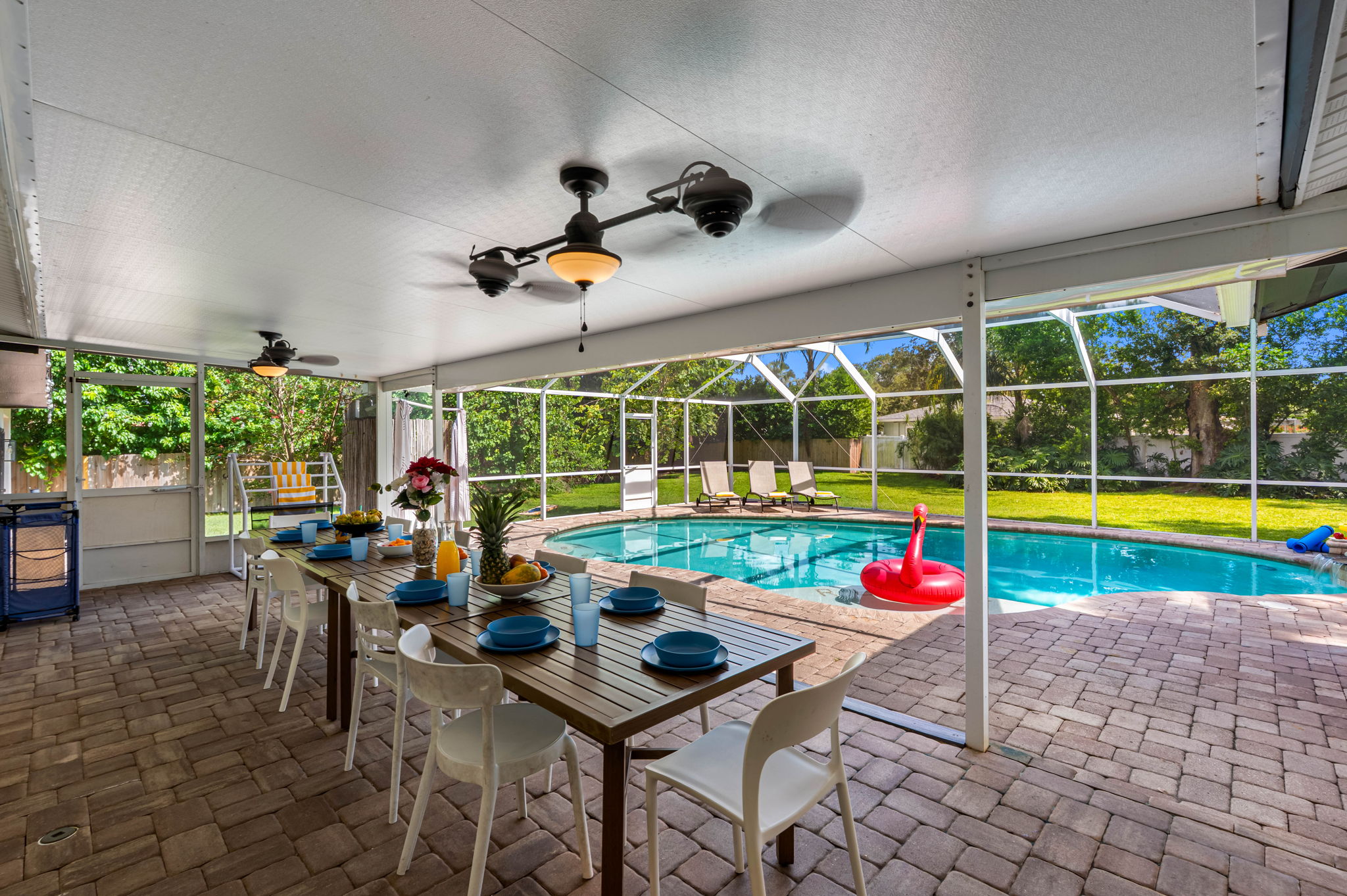 This inviting screened-in patio offers a perfect blend of indoor comfort and outdoor living, with a sparkling pool just steps away