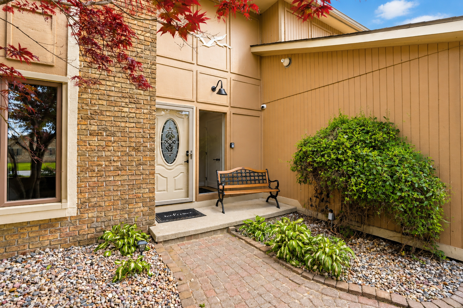 Cozy front courtyard entry with a bench and landscaped walkway, offering a welcoming and private outdoor sitting area.