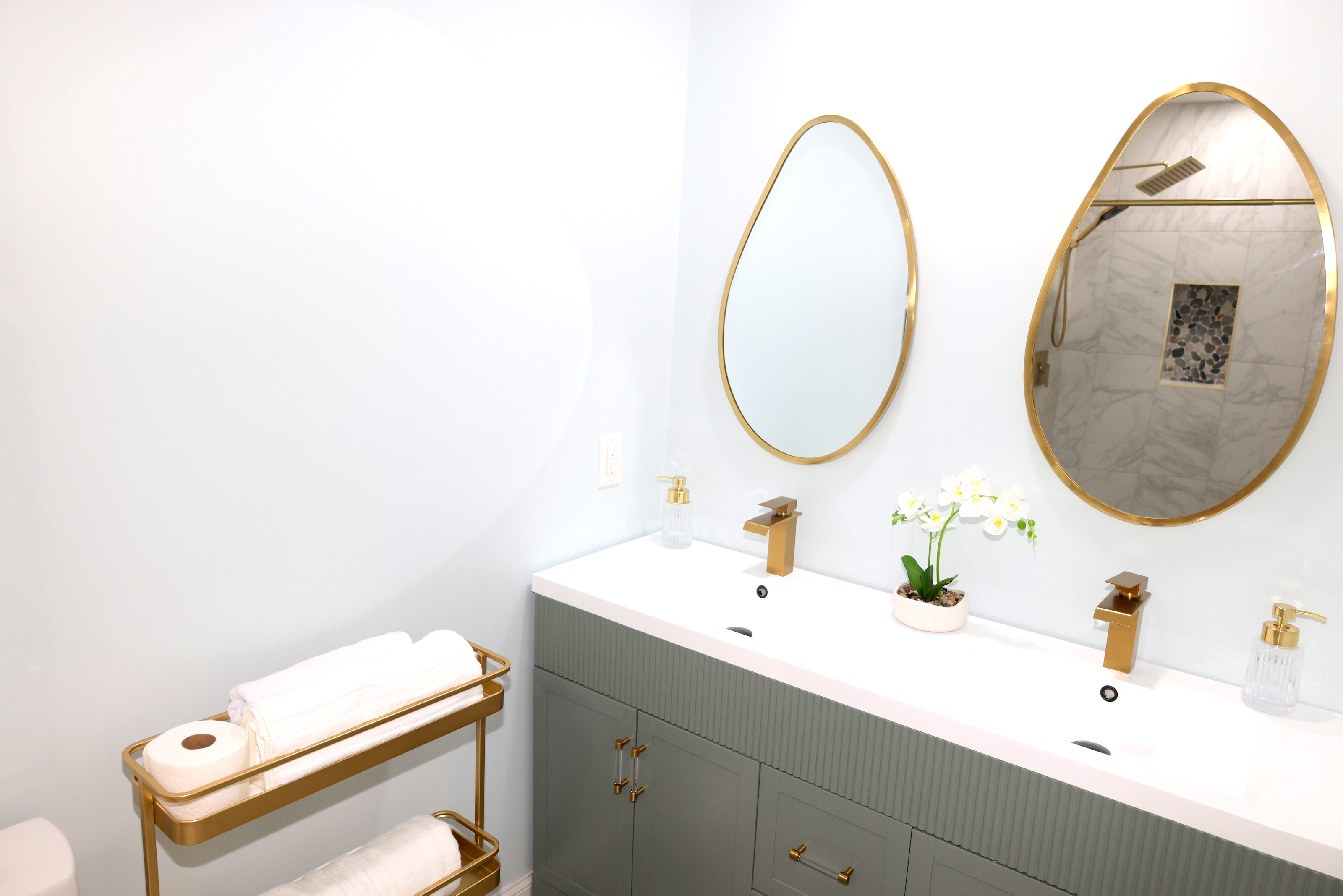 Stylish bathroom with double vanity, gold accents, fresh towels, and walk-in shower
