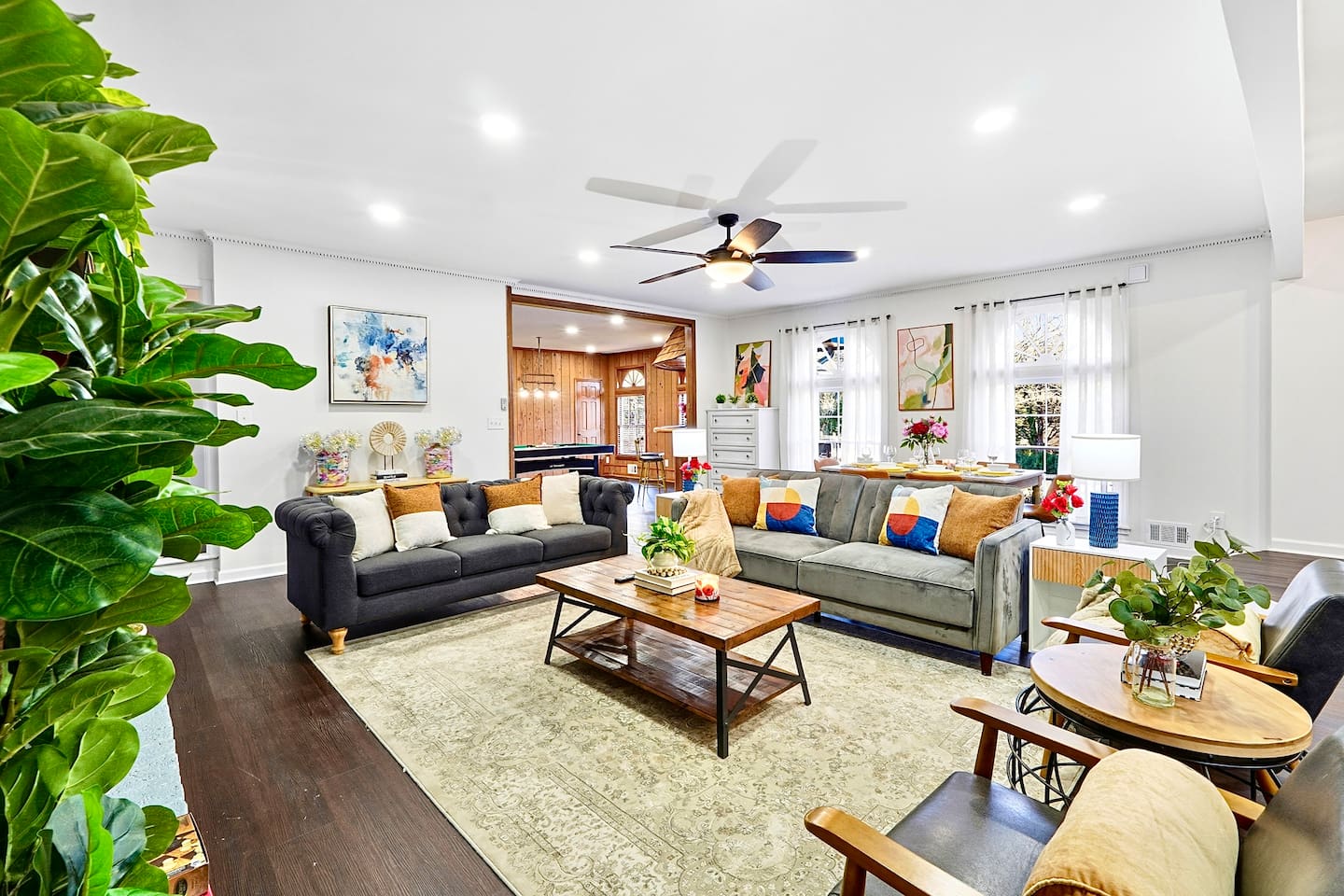 Warm and welcoming living room with two comfortable couches, two chairs, indoor plants, a cozy fireplace, and a TV powered by Google TV. Conveniently located as you walk through the front door and straight ahead from the primary side entrance. 