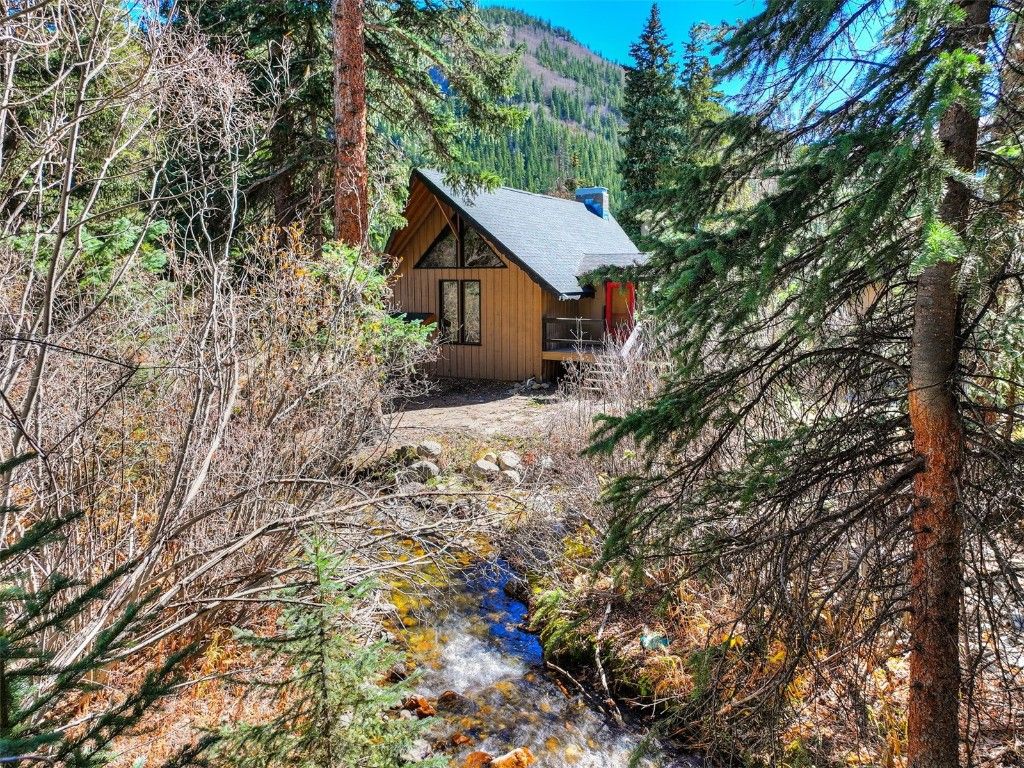 Escape to your cozy cabin retreat, where towering trees, a peaceful stream, and mountain views surround you in nature and make it all yours to unwind.