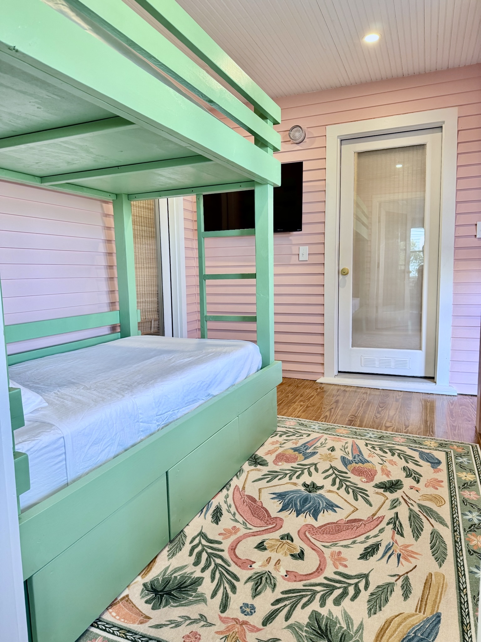 Bright coastal bunk room with built-in twin bunks and a wall-mounted TV—perfect for kids or extra guests.