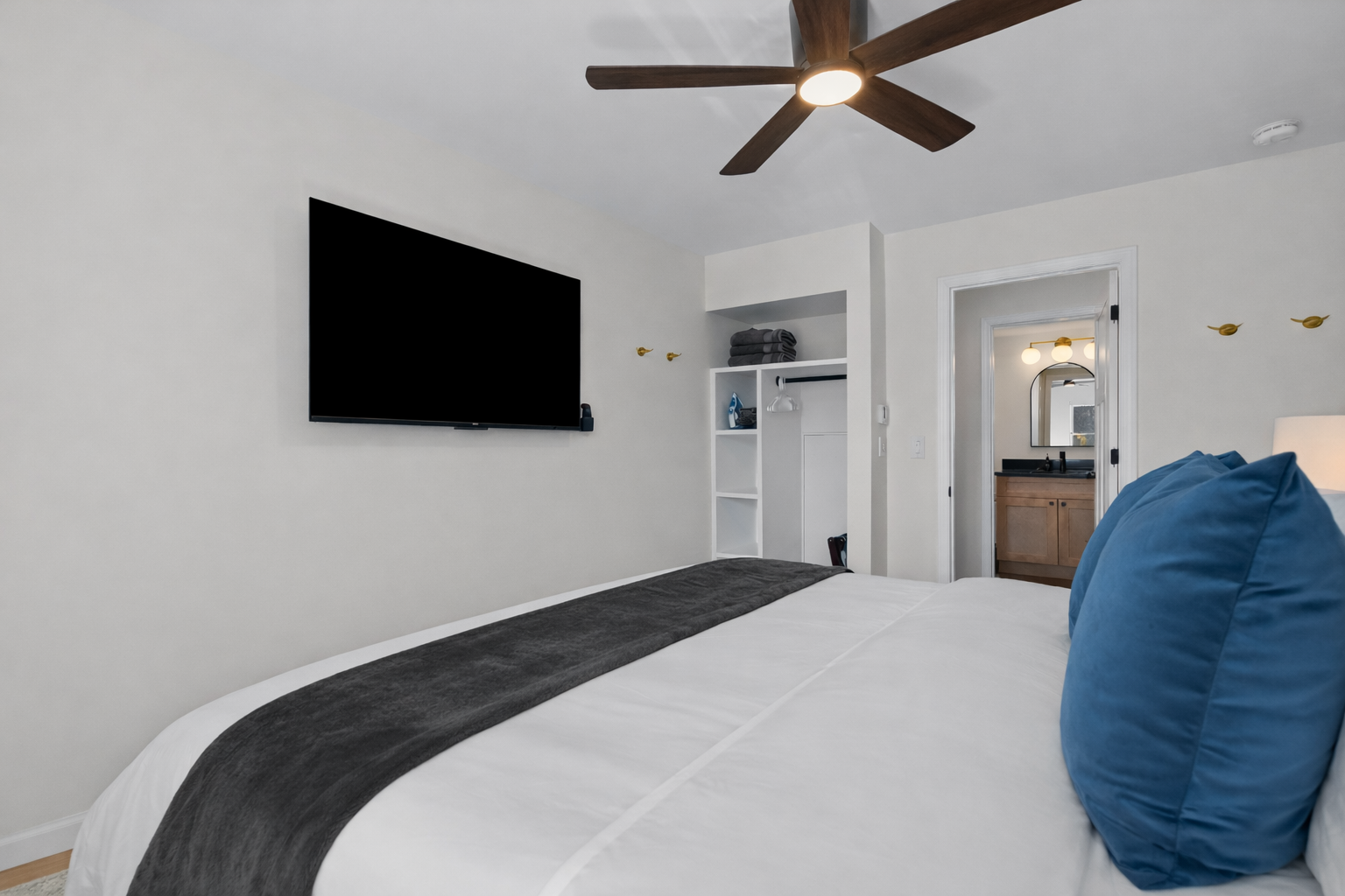Spacious, calming bedroom with a plush bed, smart TV, ceiling fan, and private en-suite—designed for comfort, relaxation, and restful nights.