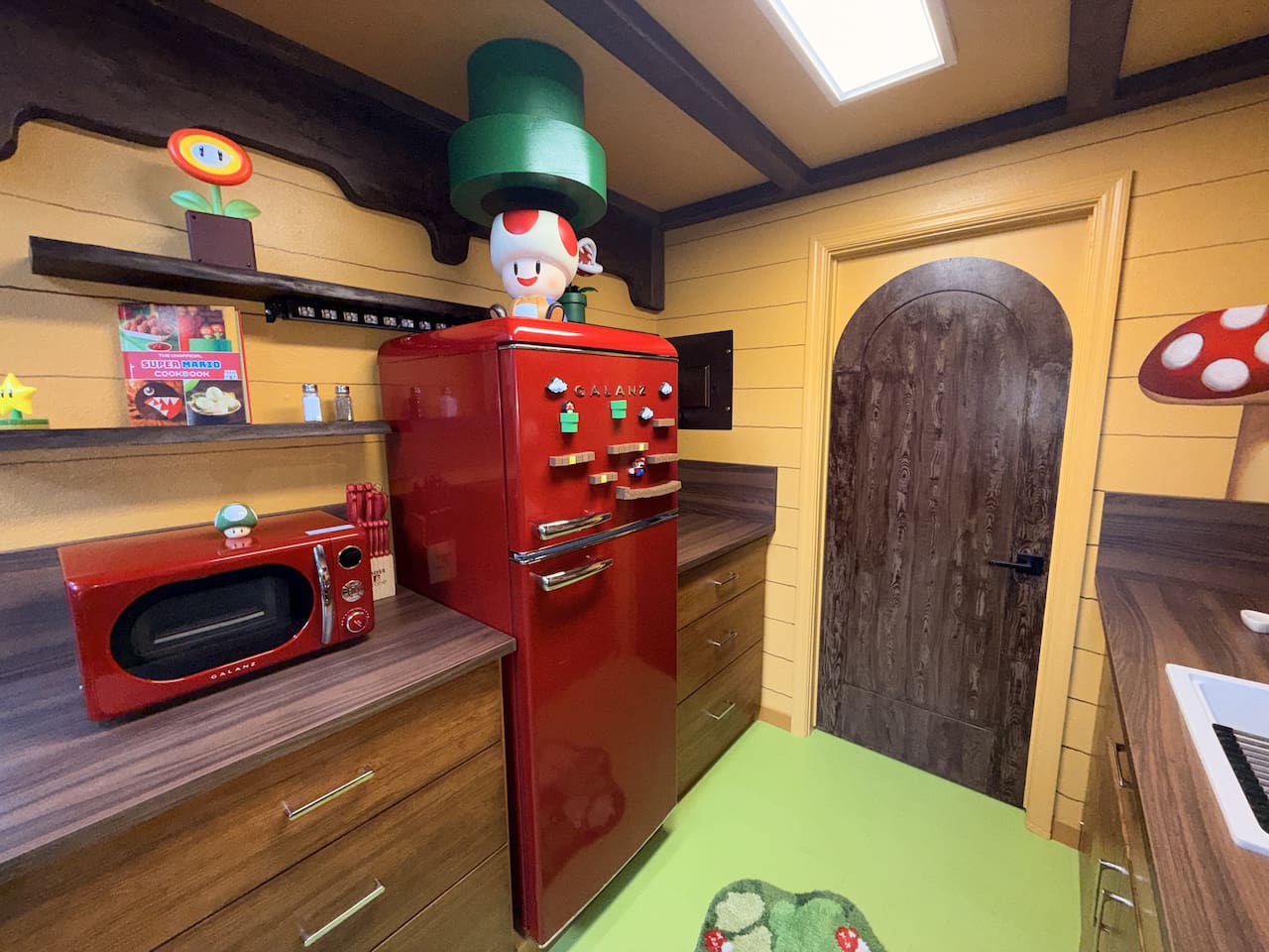 Retro red fridge and microwave corner in our Nintendo-inspired kitchen at Mario's Mini Mansion near Orlando, FL. Green pipe decor "toadstool cafe" vibe walls, and playful Super Mario accents bring joy to every cooking moment.