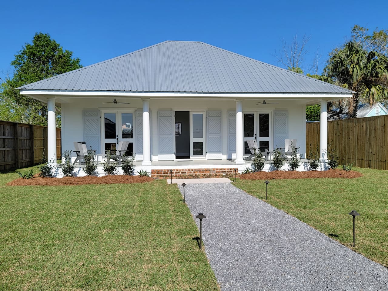 Front view of the house with large porch with comfortable chairs with view of the bay. 