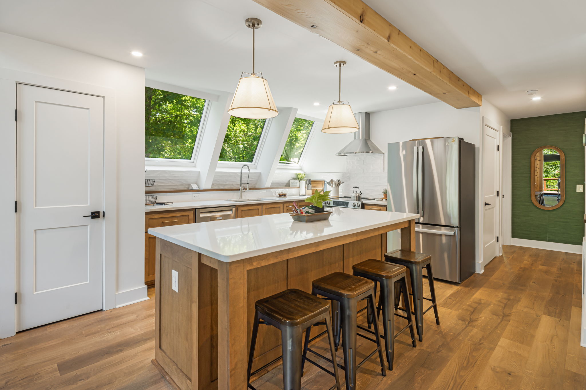 This modern and open kitchen with natural wood cabinets, quartz countertops and stainless steel appliances is fully stocked with cookware, utensils, and essentials to make meal prep a breeze. Skylights flood the space with natural light and nature views.