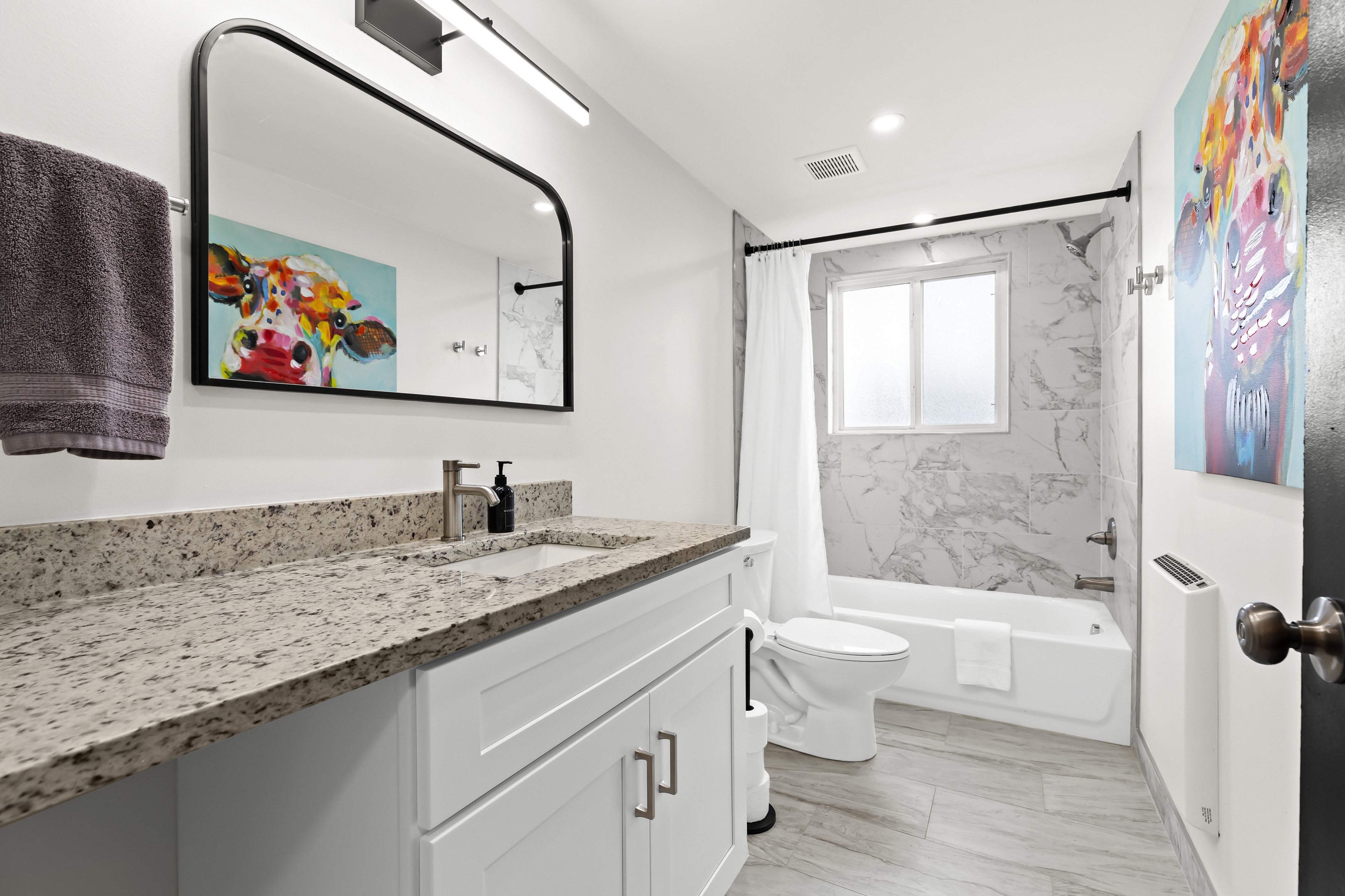 Clean and modern bathroom with full-size tub, granite vanity, and bright lighting.