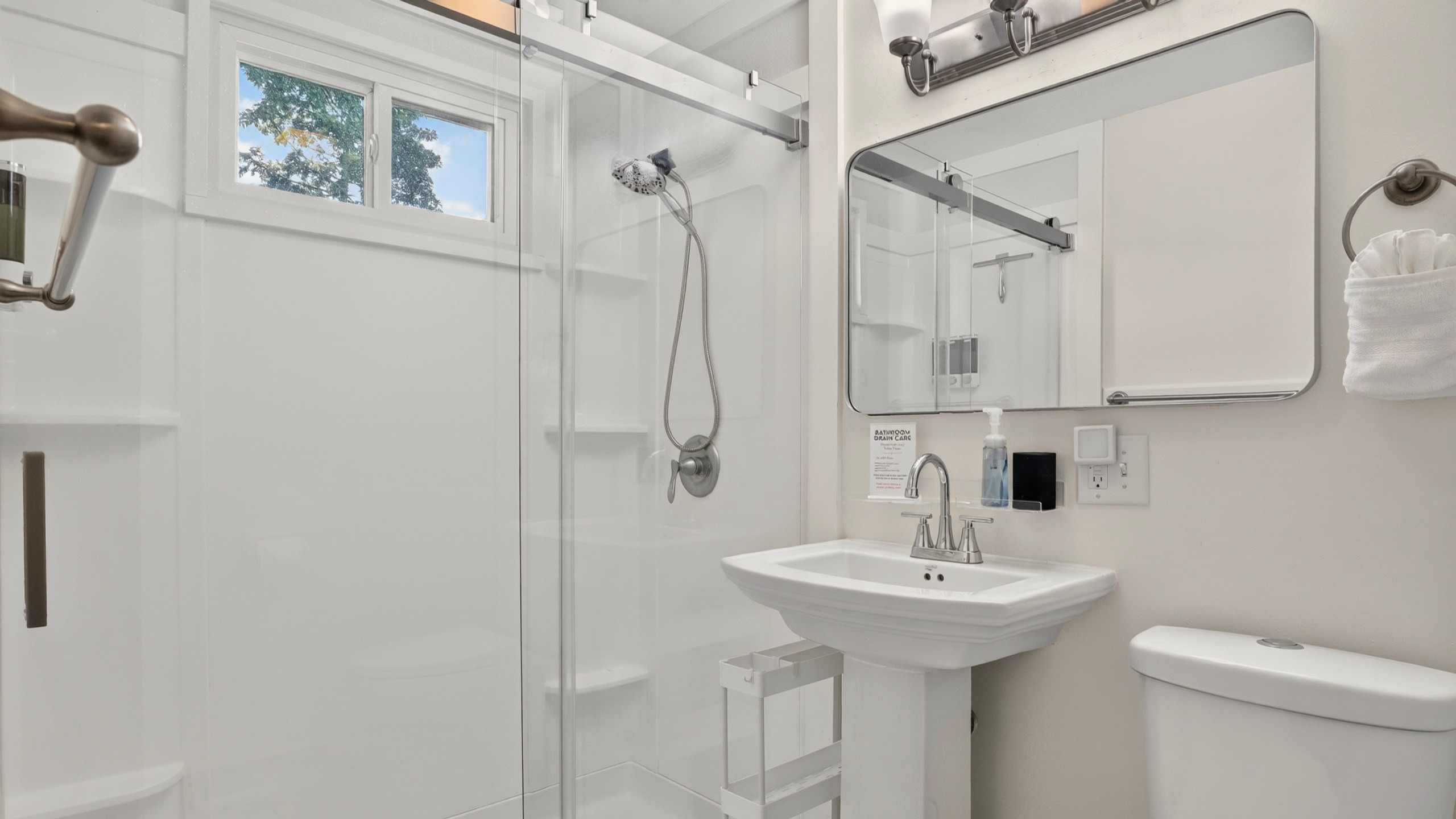 Bright, refreshed bathroom with a walk-in shower, crisp white towels, and a stocked linen closet.