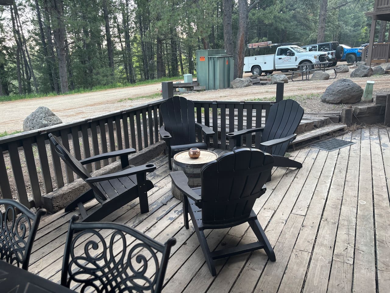 Adirondack chairs with small table in sitting are on front deck. 