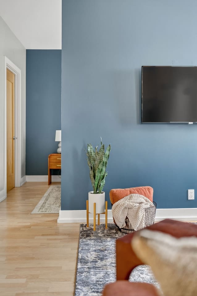 Modern design meets comfort—bold accent walls, greenery, and textured décor create a stylish yet welcoming living space. Kick back, relax, and stream your favorites on the mounted TV.