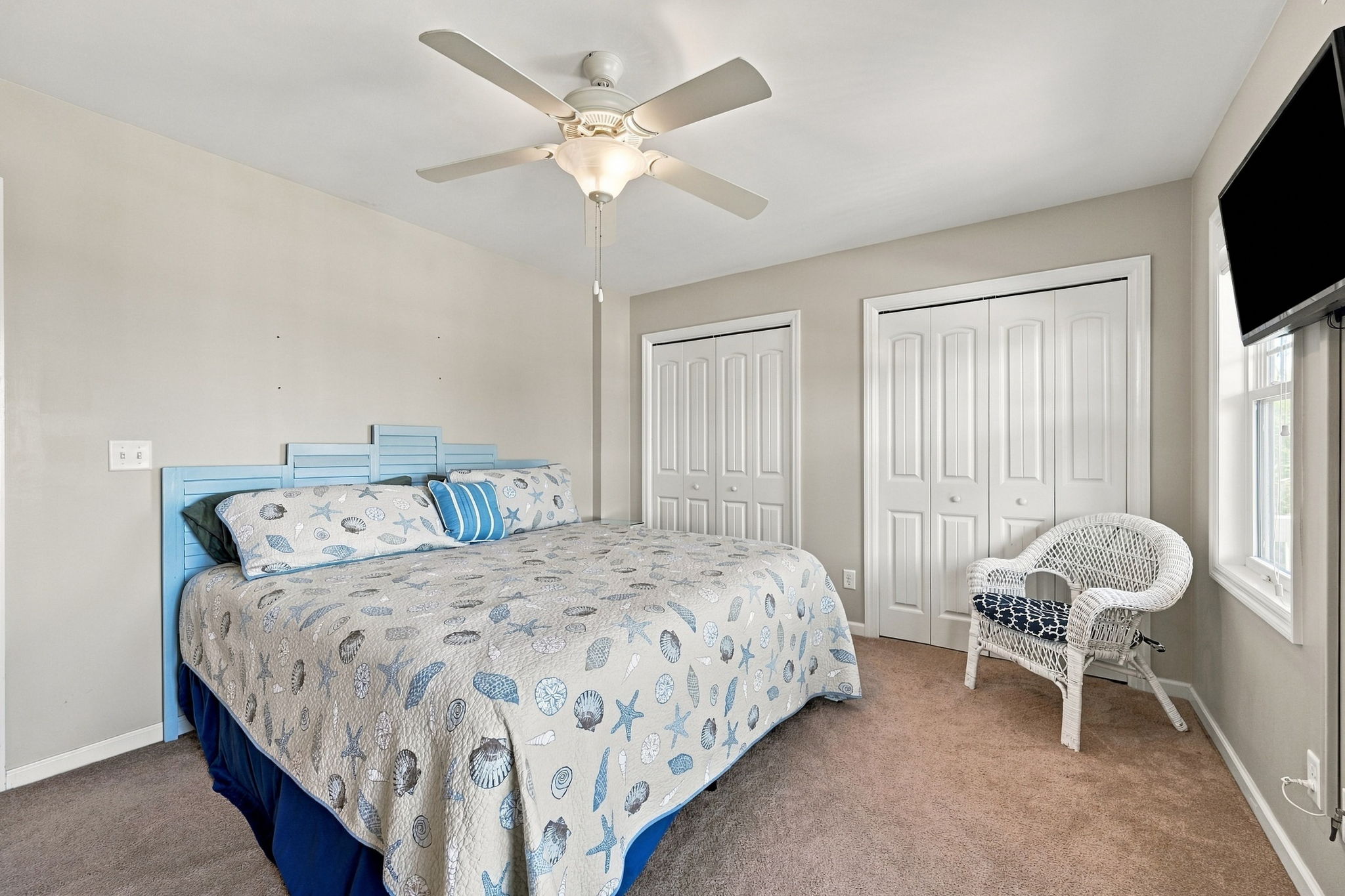 Coastal charm meets comfort in this relaxing bedroom offering plenty of storage, ceiling fan, and smart TV