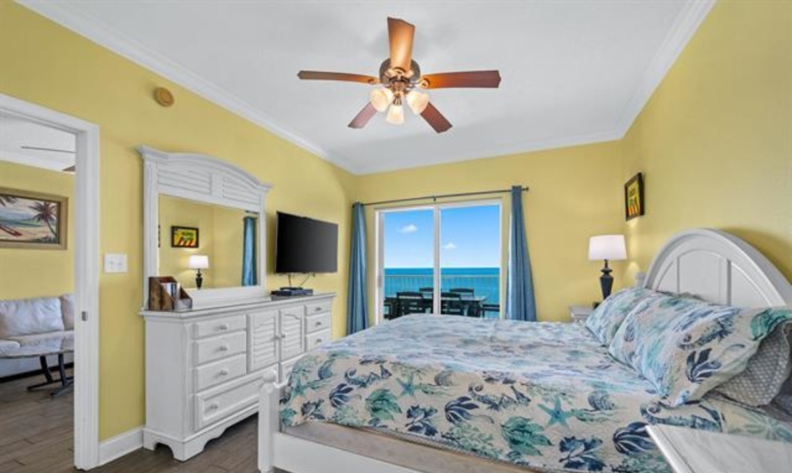 Primary Bedroom With Direct Gulf View, King Size Bed, Dresser With Mirror, 2 Nightstands, ceiling fan, double closet, 50" wall mounted Smart TV, Direct Balcony Access & Ensuite Full Bathroom