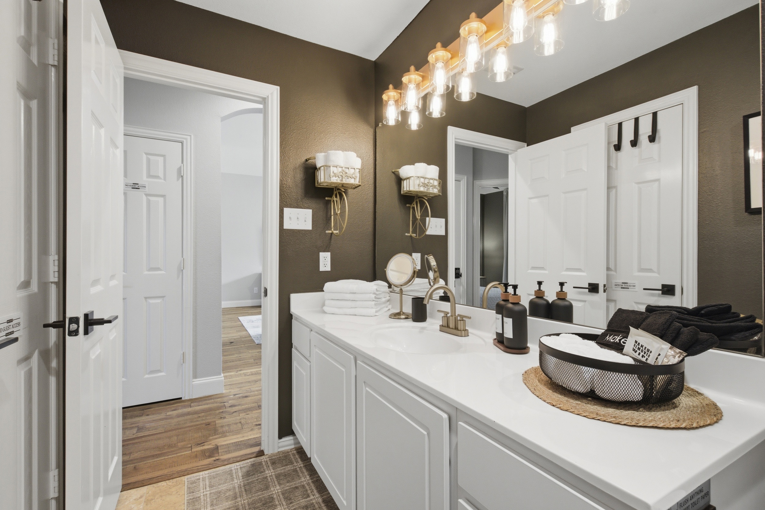 Guest Bathroom Vanity area with mirror, soft lighting, and ample counter space for two. Stocked with essentials by Ginger Lily Farms.
