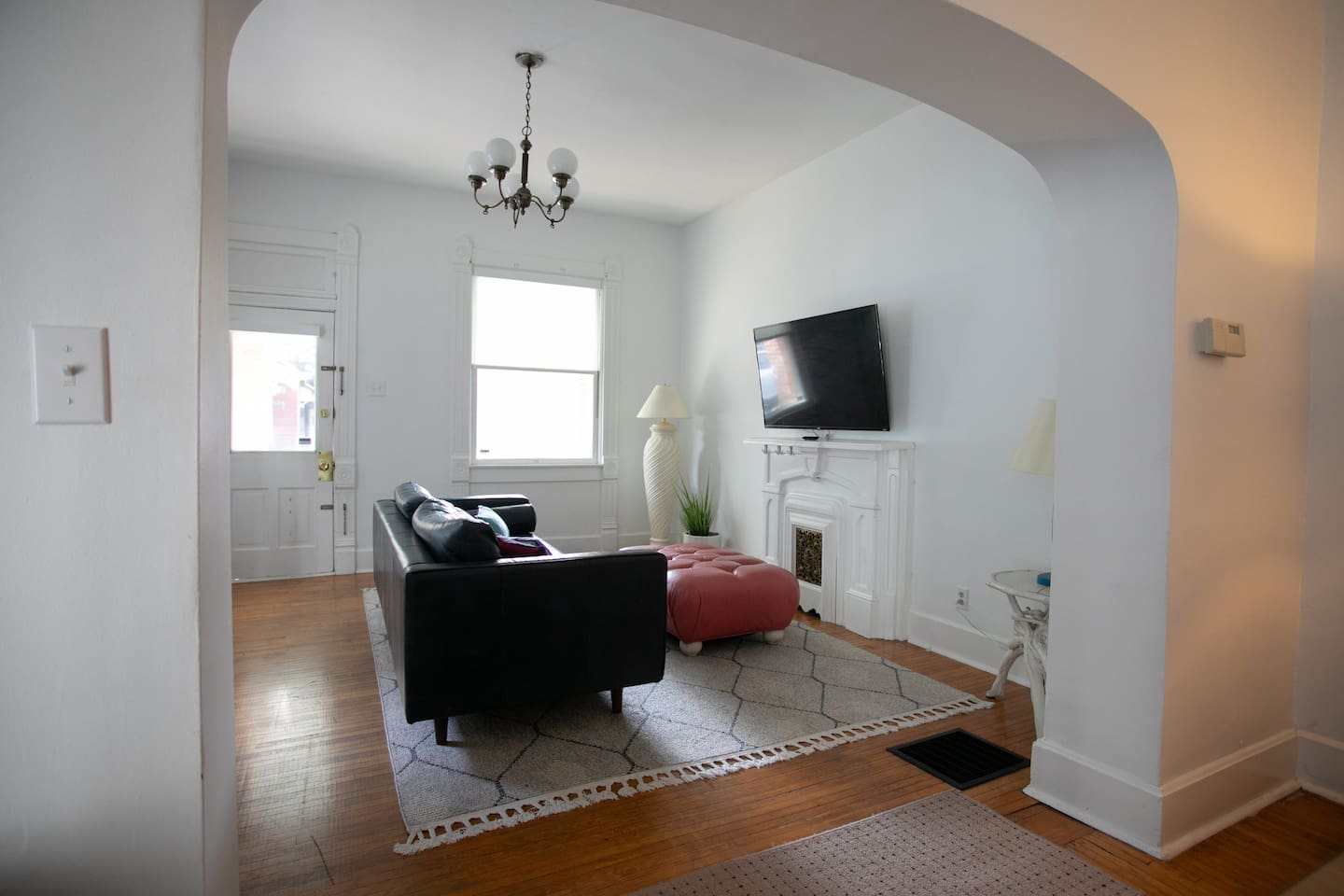 A bright, open view highlighting the room’s scale, natural light, classic arches, and early-1920s charm.