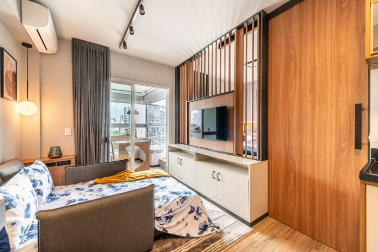 Ambiente versátil com sofá-cama montado, ar-condicionado, cortinas blackout, TV giratória e acesso direto à varanda — conforto completo para até 4 hóspedes em São Paulo.
