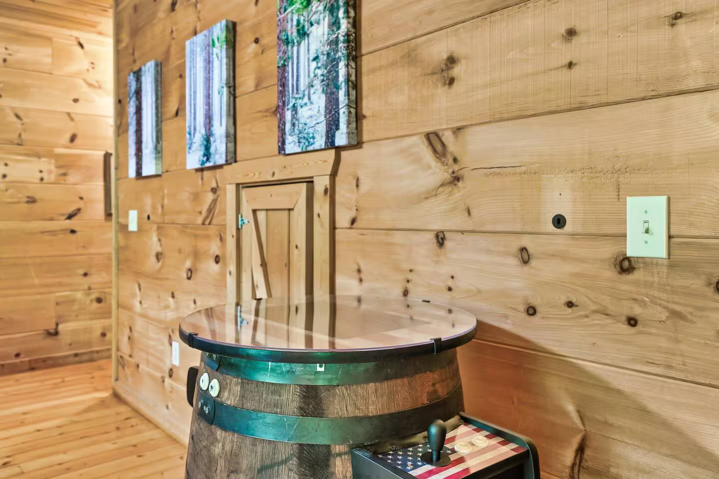 A charming addition to this rustic space, the Pac-Man arcade table boasts a patriotic design and sits adjacent to comfy bunk beds, offering entertainment and relaxation in one spot.