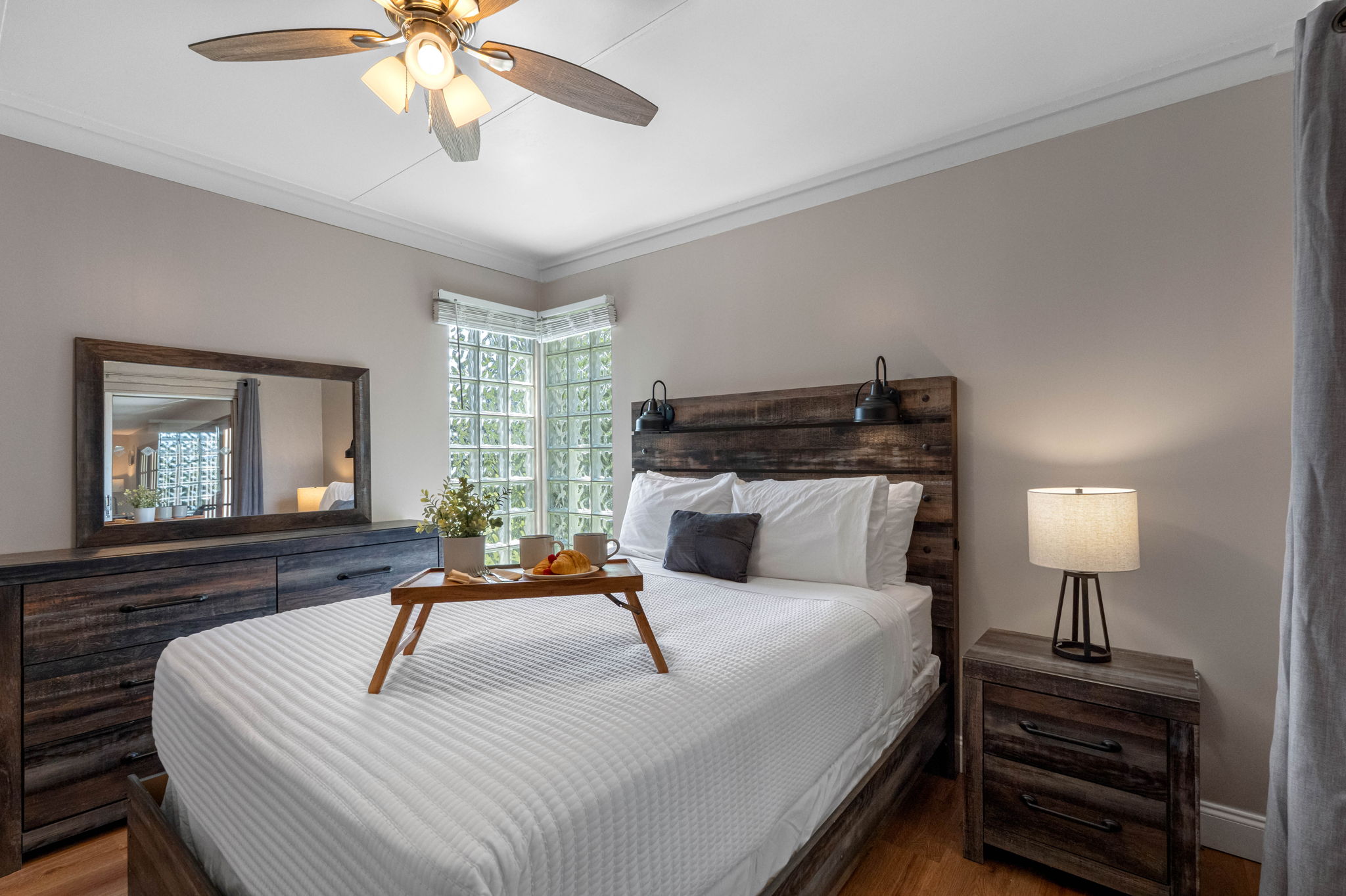 The natural wood furniture and headboard add a rustic charm, while modern touches create a balanced and stylish look.