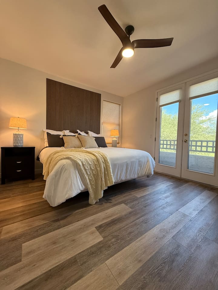 King bedroom with soft layered bedding, bedside lighting, and private balcony access for a comfortable stay.