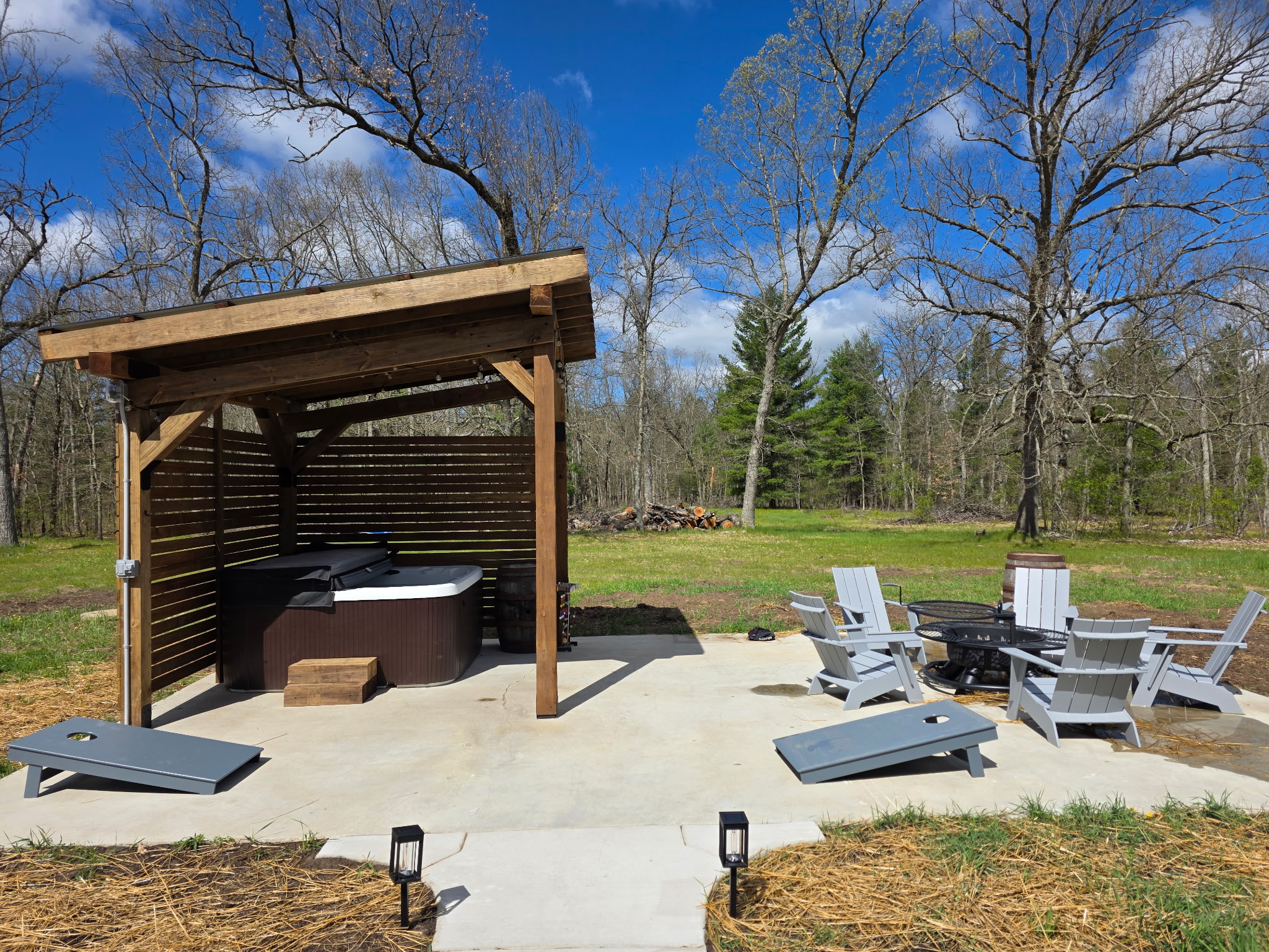 Hot tub patio with firepit and corn hole.