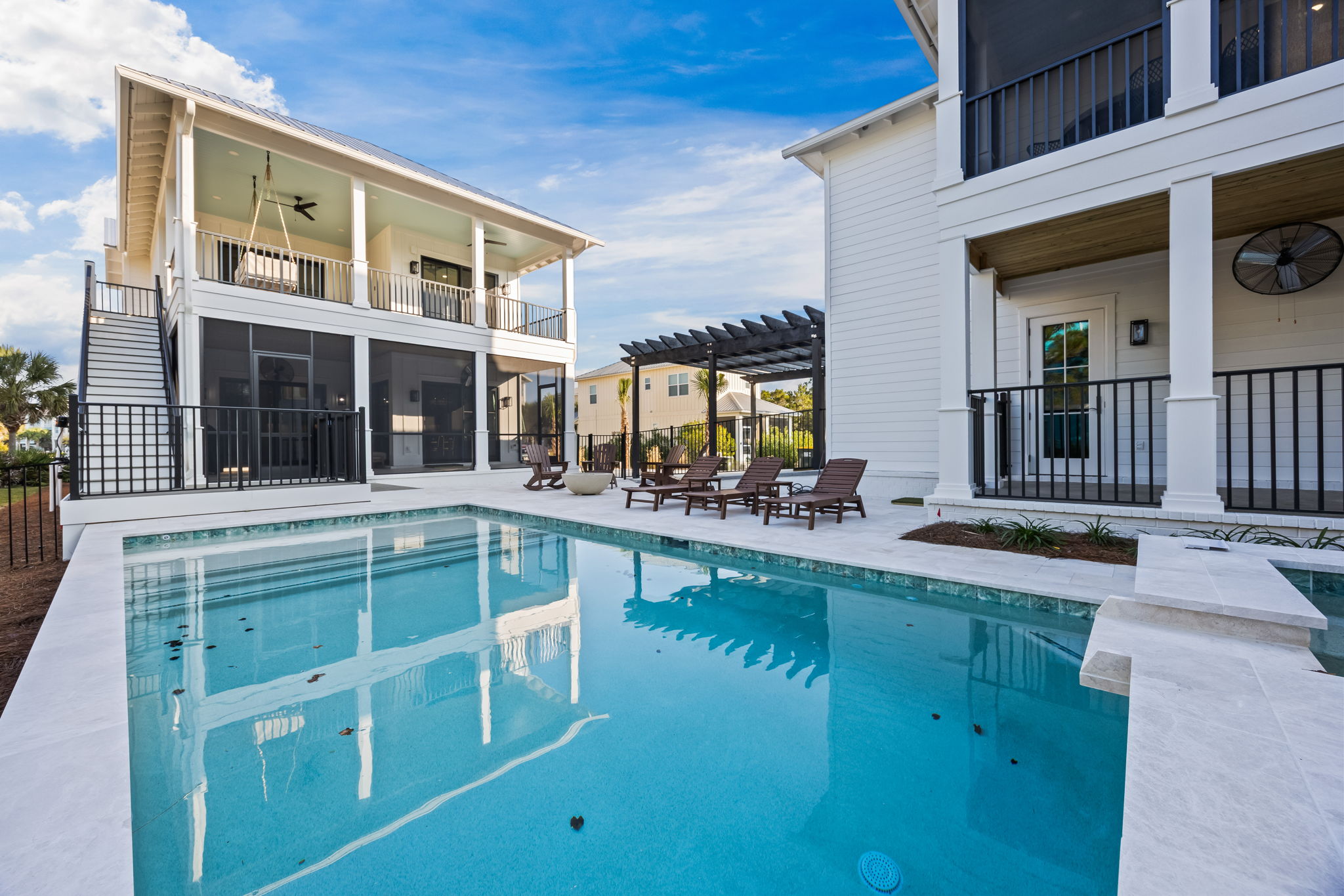 Private pool courtyard framed by both homes, with four porches surrounding the space, screened lower lounging areas, and direct outdoor staircase access from the upstairs bedrooms—designed for effortless indoor-outdoor living.