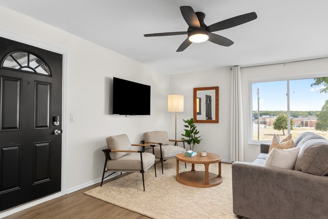 Relax in this sunlit living room, complete with a comfy sofa, leafy views, and a large Smart TV.