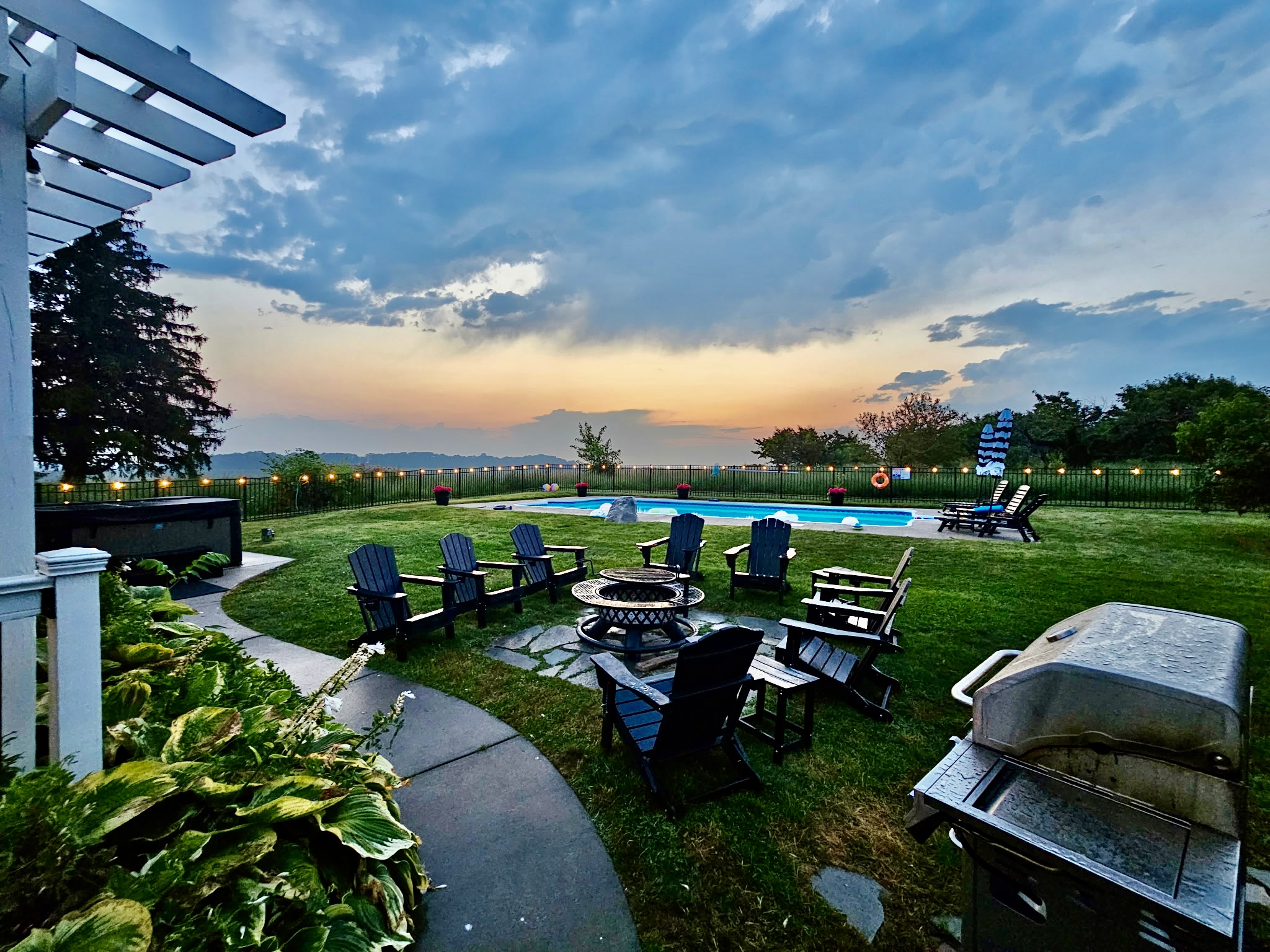 Enjoy peaceful early mornings, sunny afternoons, and memorable evenings in this private backyard featuring a pool, hot tub, fire pit, and sweeping country views.