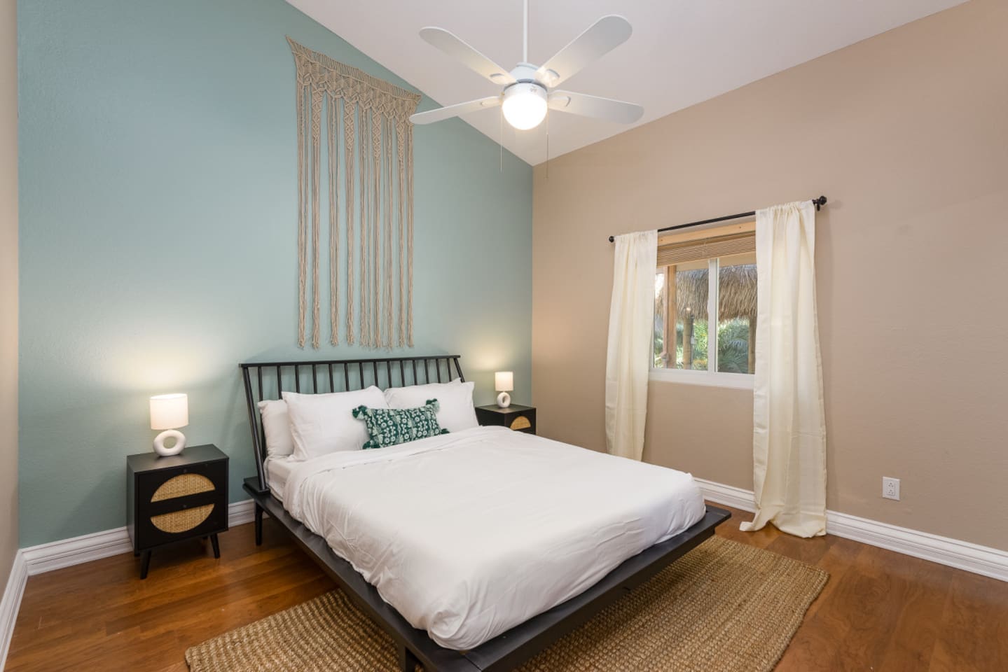 Guest bedroom with a queen bed, ceiling fan, bedside lighting, and a calm accent wall for a restful stay.
