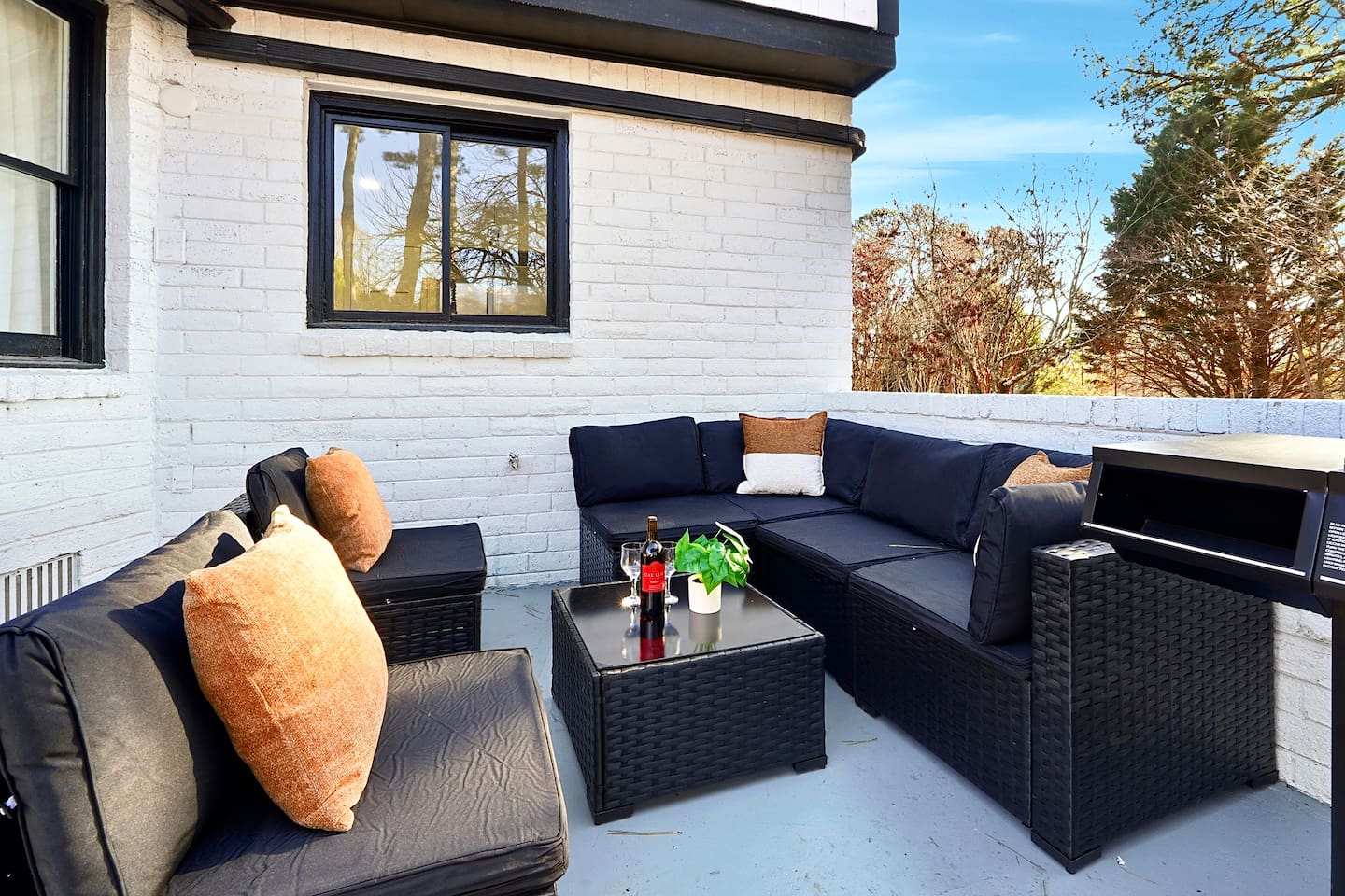 Inviting patio with black outdoor furniture, beige chairs, and a propane grill. A great space to relax, dine outside, or enjoy time with friends and family.