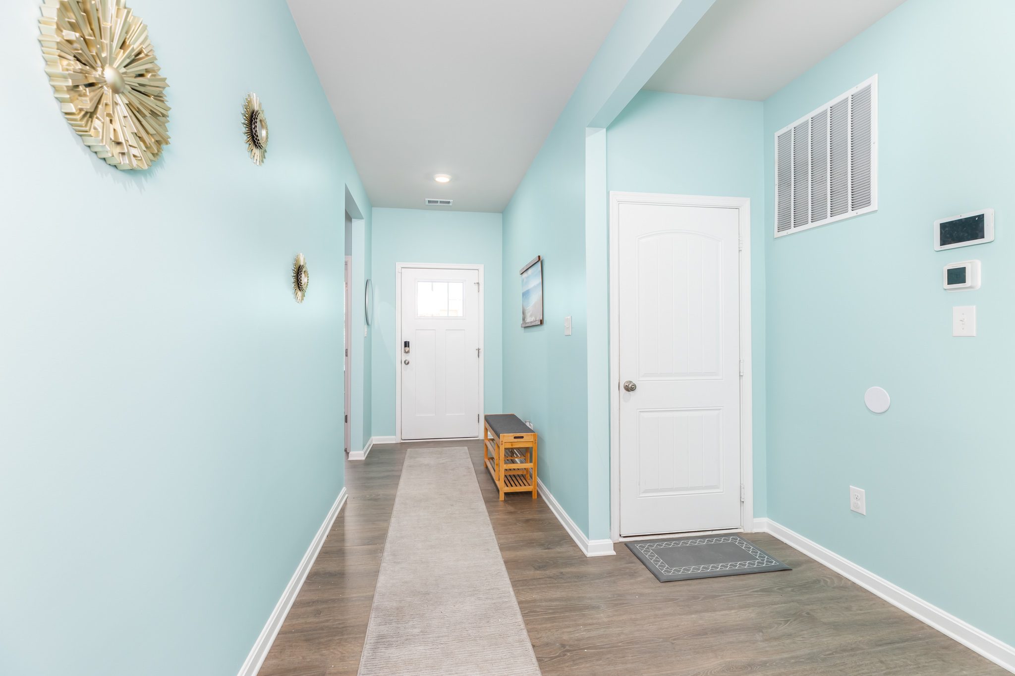 Step into a sunlit foyer painted in coastal hues, with a durable runner rug and convenient bench—perfect for shedding sandy shoes and greeting guests.