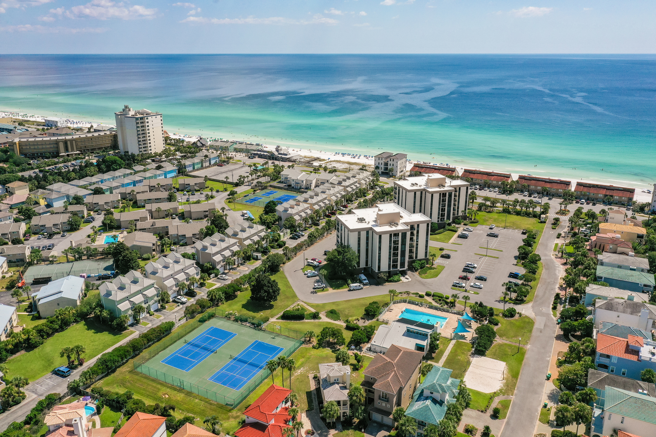 Aerial view of Oceanic View inside The Enclave community—featuring nearby tennis courts, community amenities, and beautiful private beach access just a short distance away. 🌊🏖️🎾