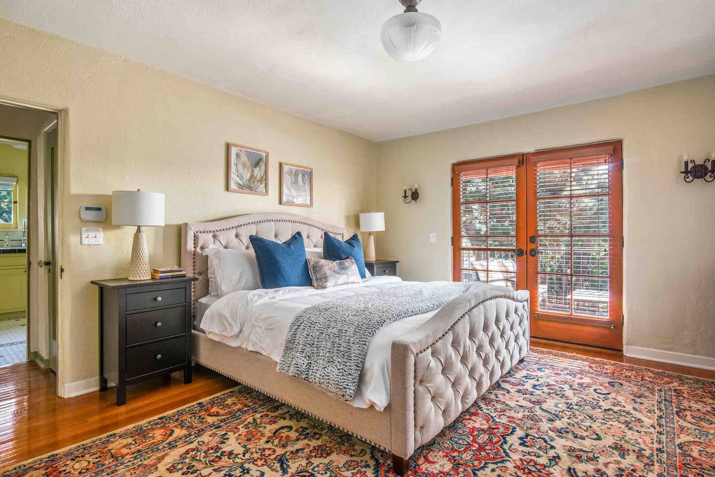 The spacious primary bedroom has a large closet, a tall dresser, a TV over a second dresser, and double French doors which open to the third private terrace. 