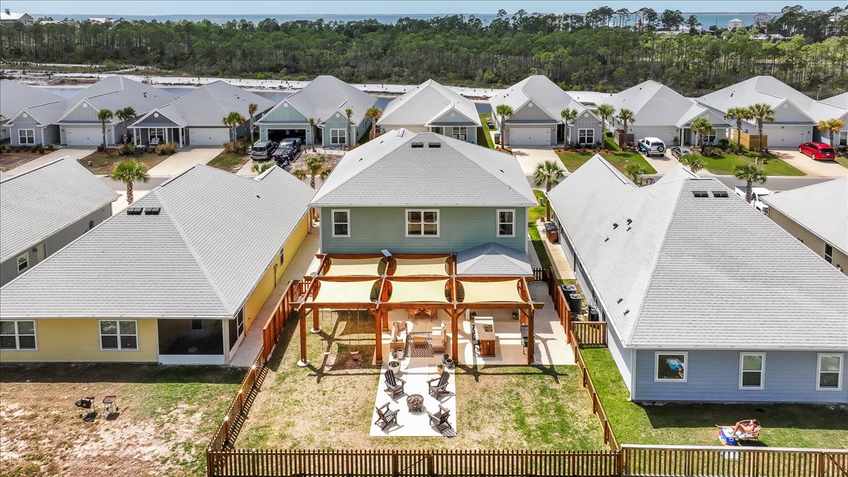 Enjoy outdoor living in this spacious fenced backyard with a fire pit, grill, comfortable seating, and a relaxing swing