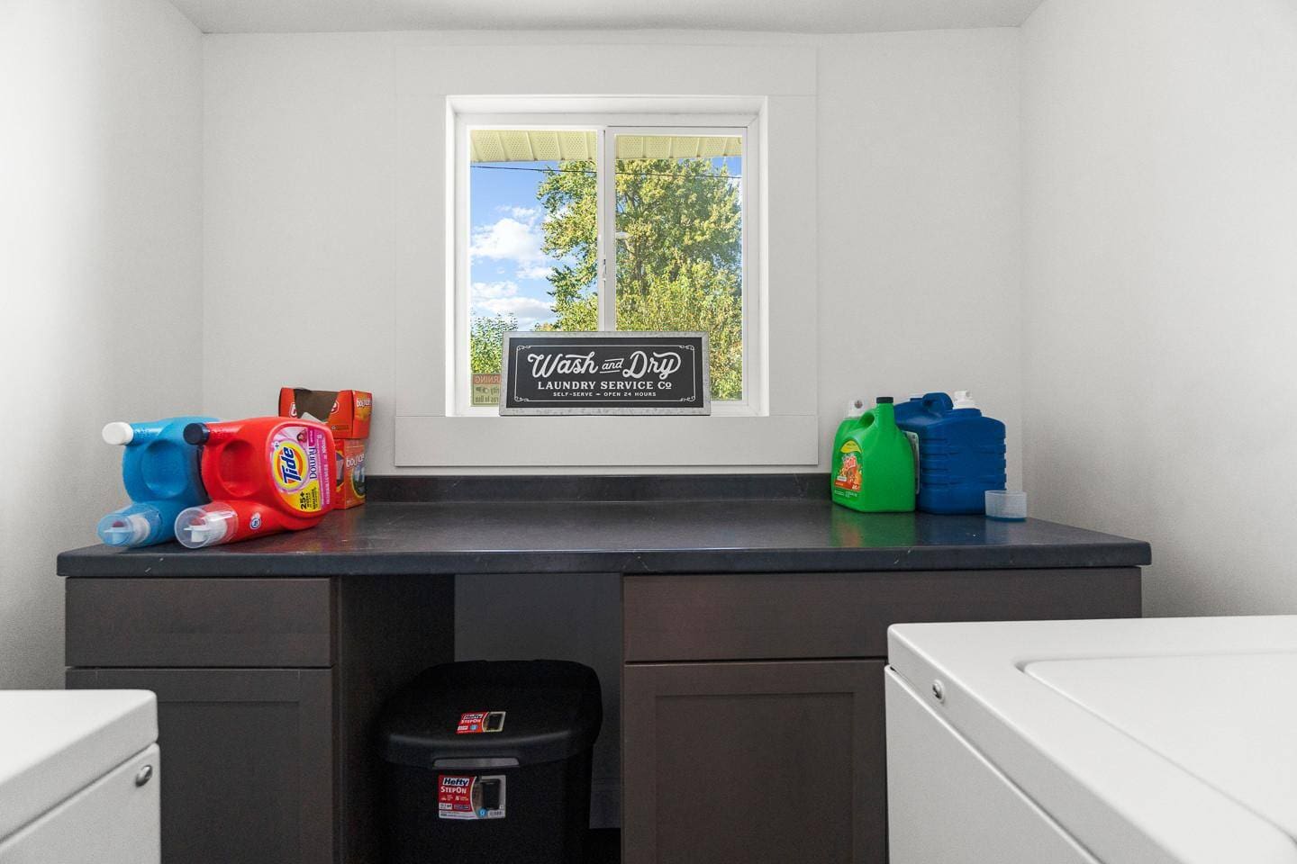 Bright laundry room featuring a window for natural light, coin-operated machines for convenience, and charming decor to make the space inviting.