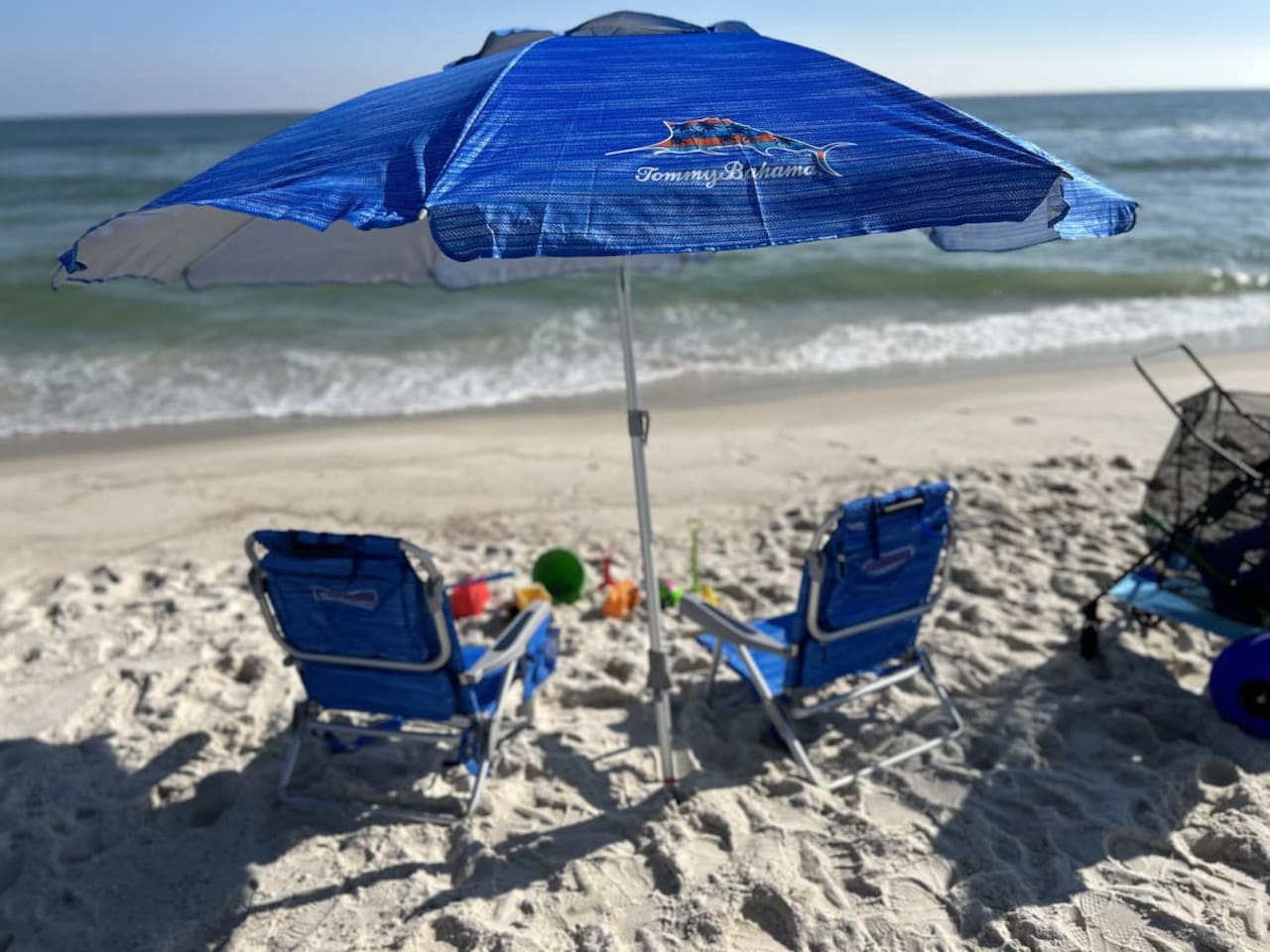 Beach bliss with Tommy Bahama shade, comfy chairs, and soothing ocean waves.