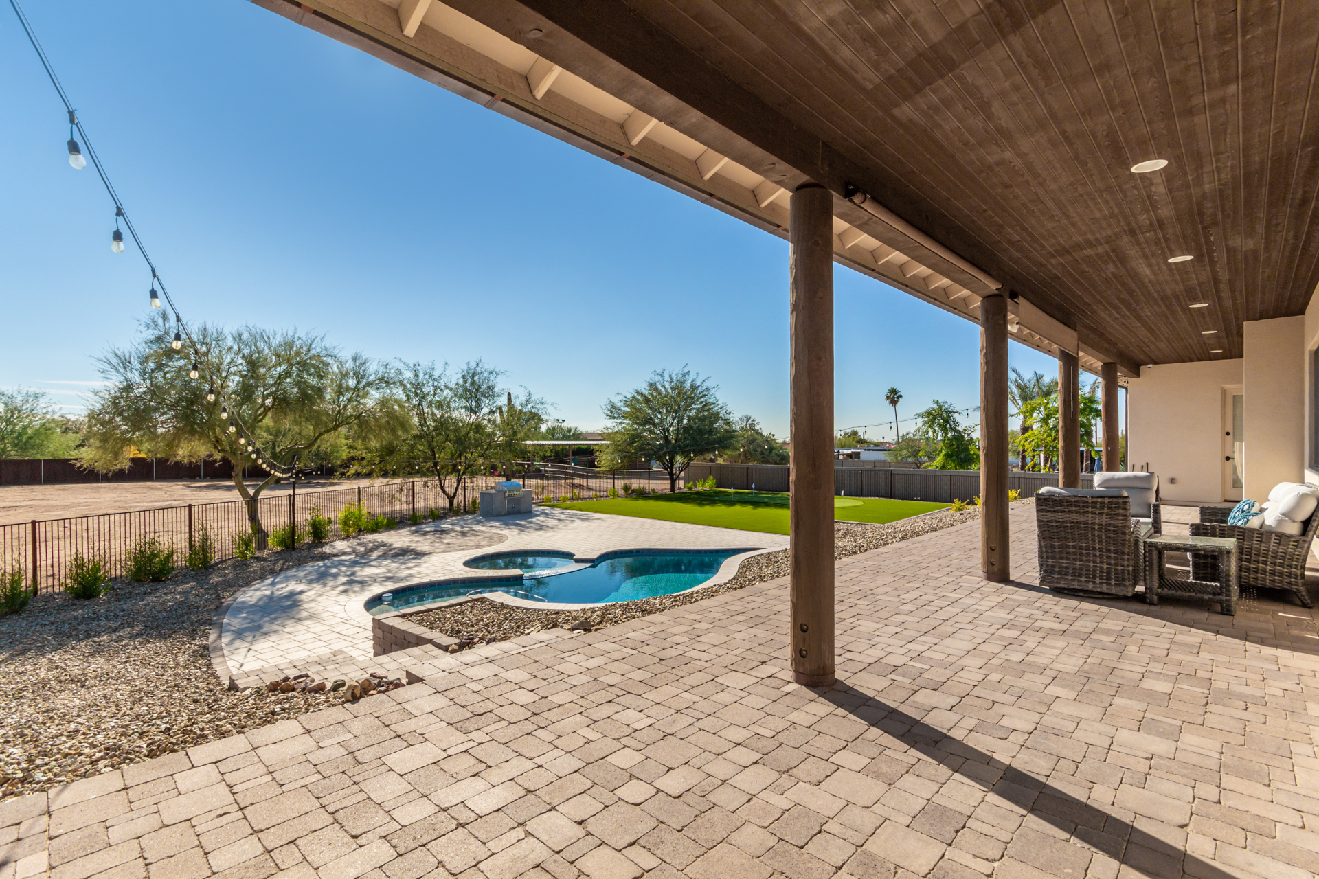 large covered patio & awesome backyard w/ putting green, turf area for yard games & sparkling pool and spa