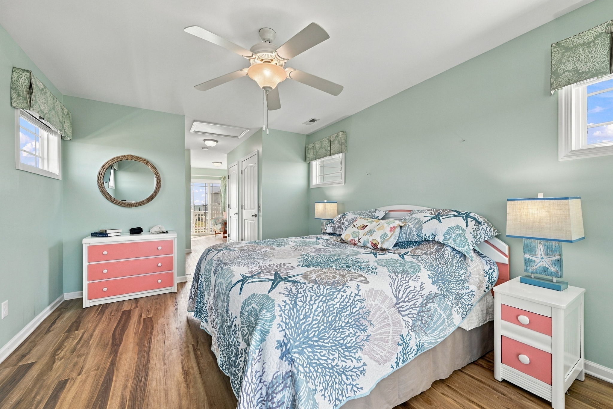 Relaxing king bedroom featuring coastal-inspired bedding, beautiful natural light, and charming furnishings