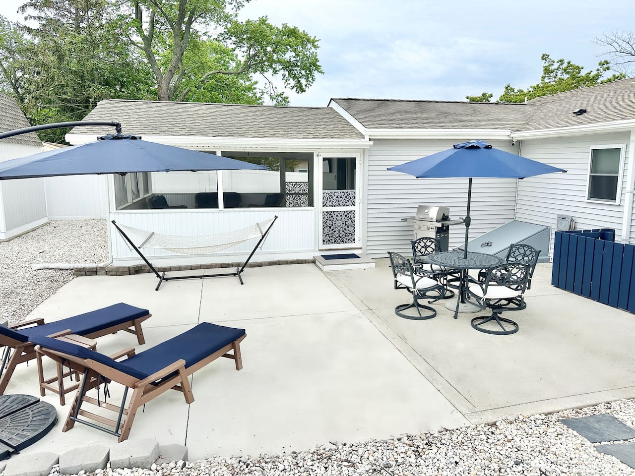 Maximize your vacation in our fully equipped backyard. Features include a gas grill, patio dining for four under a blue umbrella, lounge chairs for sunbathing, and a relaxing hammock. The perfect setup for a summer afternoon BBQ!
