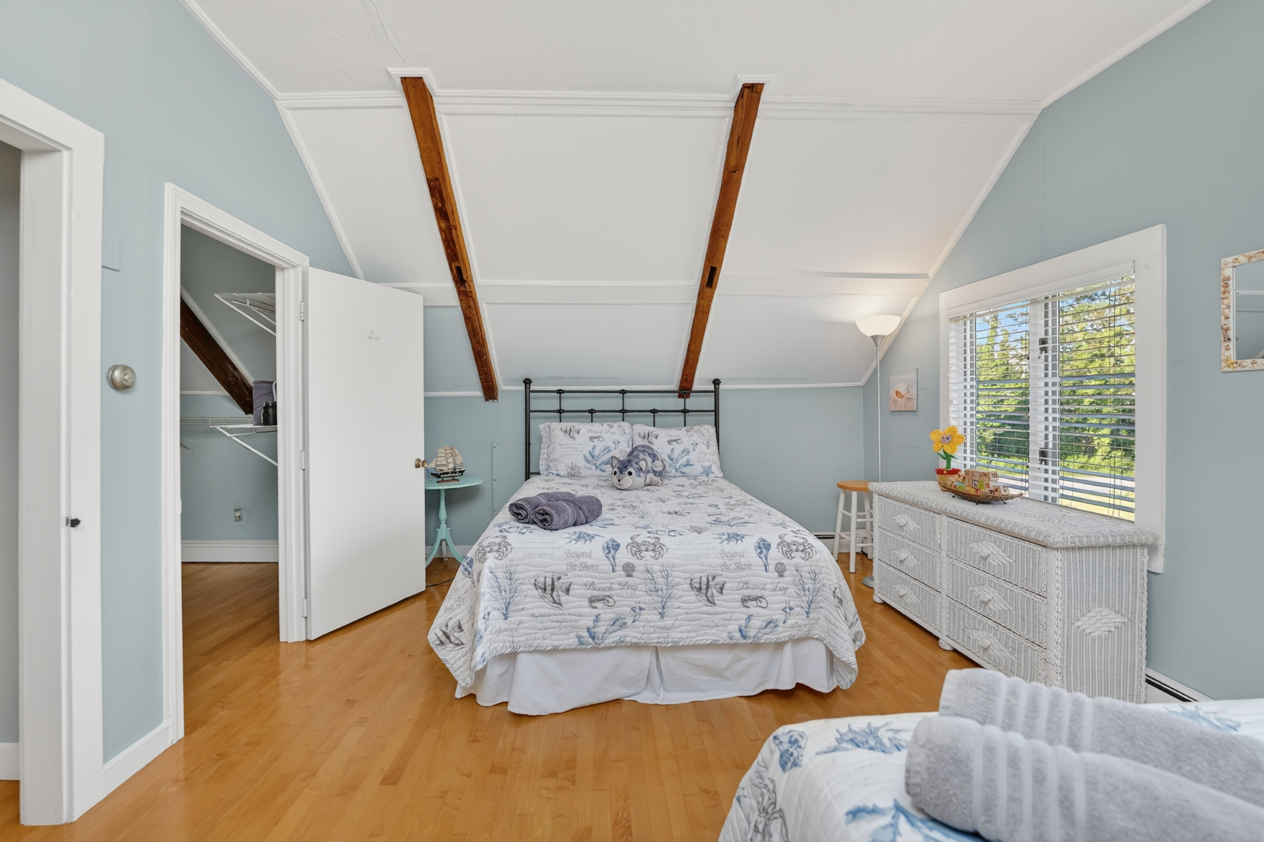 Inviting upstairs bedroom with cozy furnishings, ample natural light, and relaxing coastal charm.