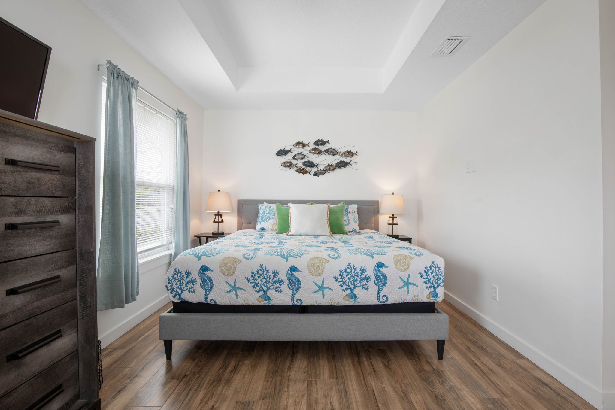After a day by the water, retreat to this calm coastal bedroom, where soft light, seaside details, and a plush bed invite you to stretch out, exhale, and wake refreshed for another easy morning at the beach.